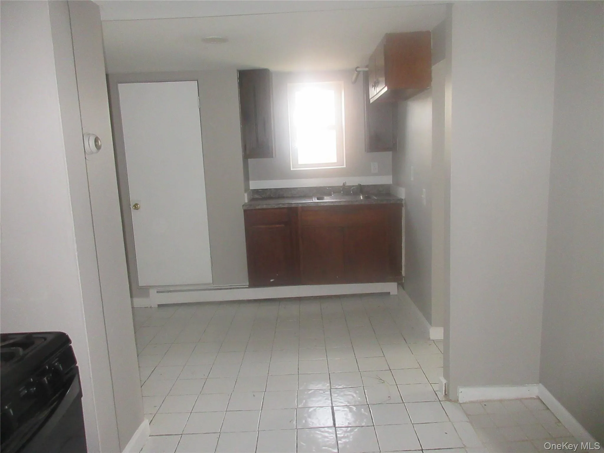Kitchen featuring black gas range oven, light tile patterned floors, and brown cabinetry Kitchen featuring black gas range oven, light tile patterned floors, and brown cabinetry