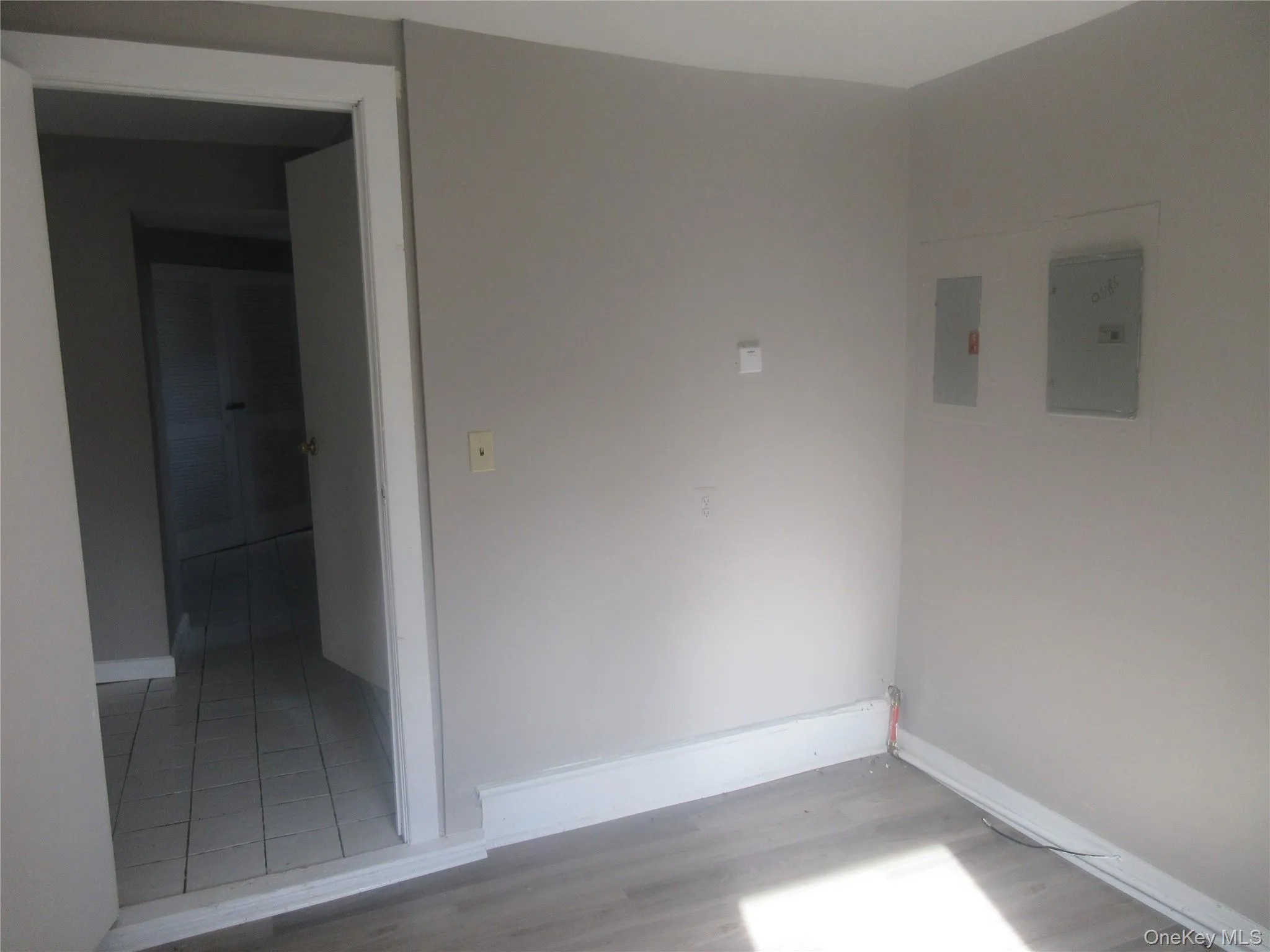 Empty room featuring light wood-type flooring and electric panel Empty room featuring light wood-type flooring and electric panel