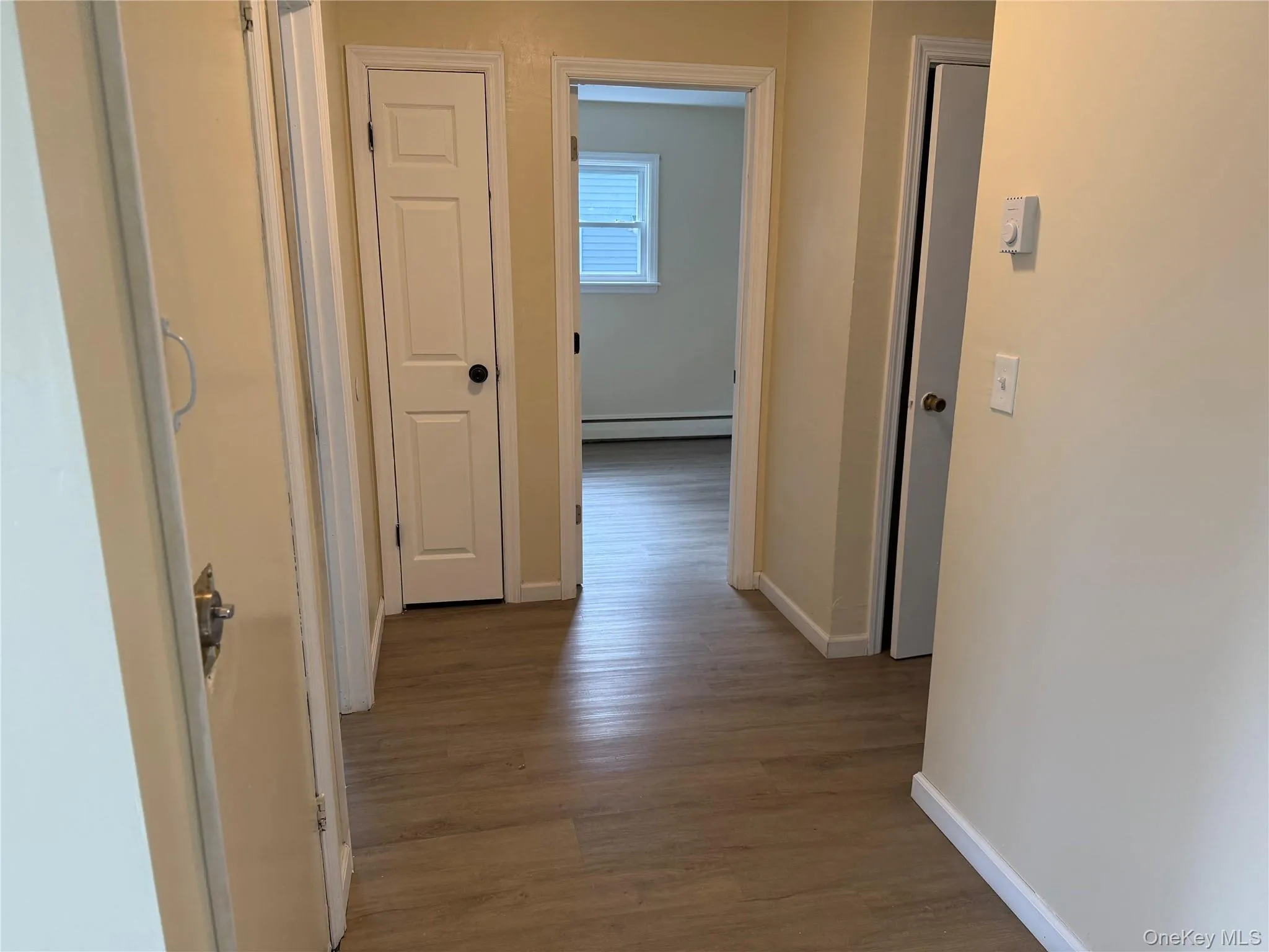 Hallway with light wood-style flooring and a baseboard radiator Hallway with light wood-style flooring and a baseboard radiator