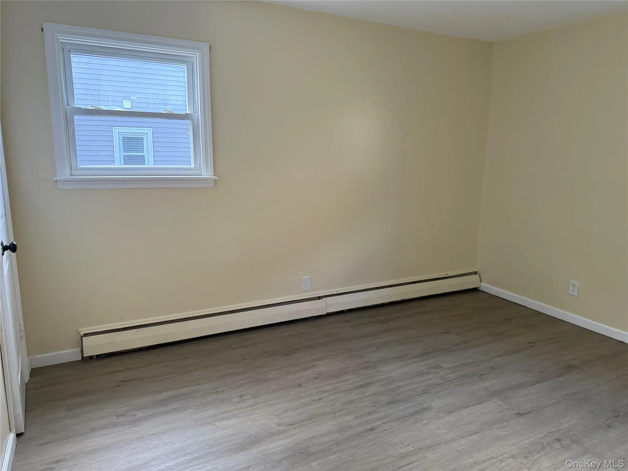 Empty room featuring a baseboard radiator and wood finished floors Empty room featuring a baseboard radiator and wood finished floors