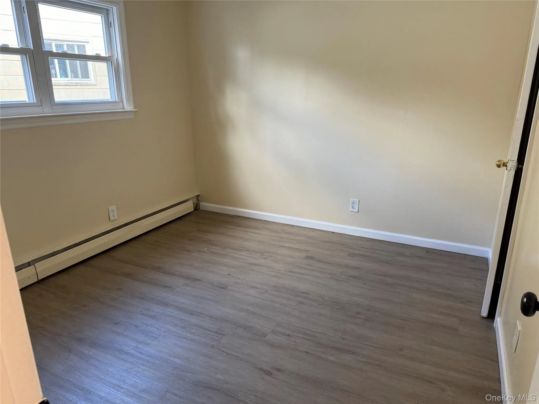 Empty room with a baseboard heating unit and wood finished floors Empty room with a baseboard heating unit and wood finished floors