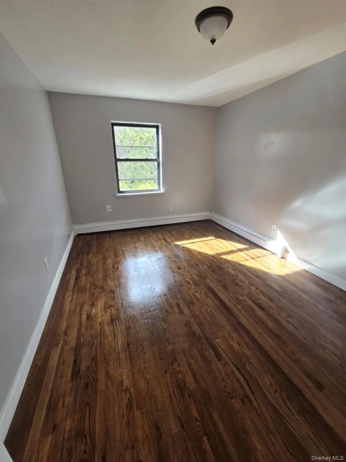 Spare room featuring dark wood-type flooring and a baseboard heating unit Spare room featuring dark wood-type flooring and a baseboard heating unit