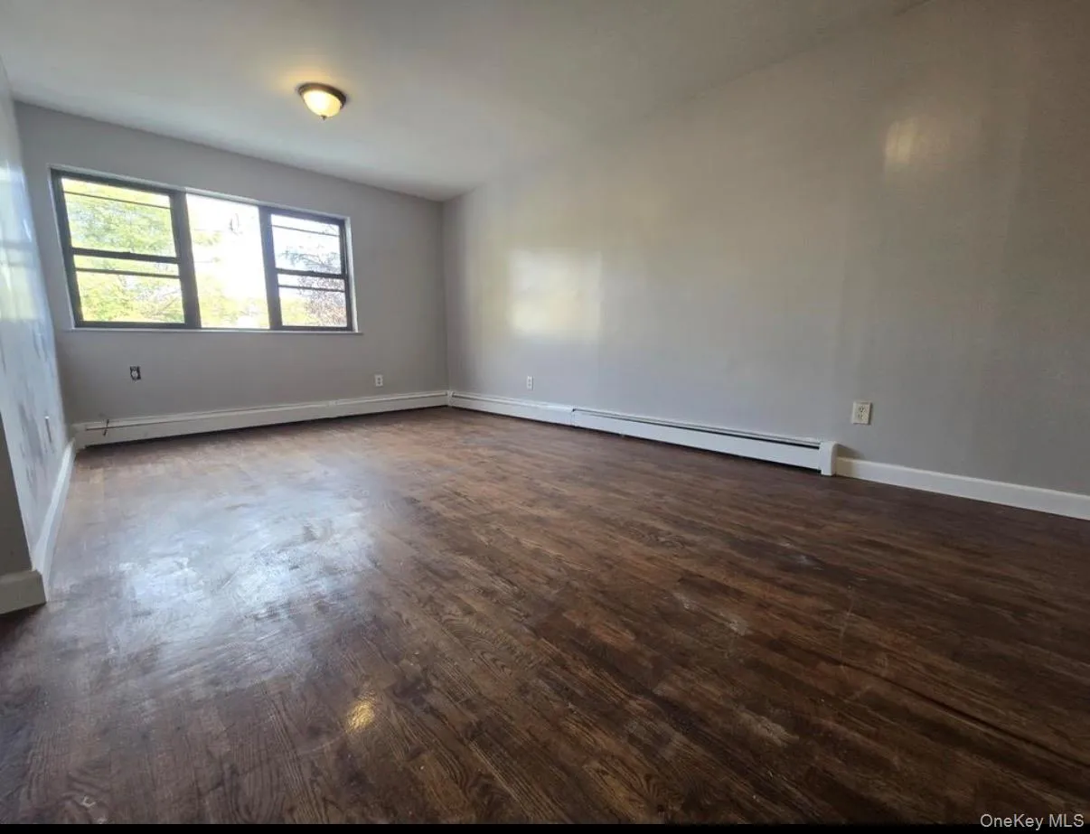 Spare room with dark wood-style flooring and a baseboard heating unit Spare room with dark wood-style flooring and a baseboard heating unit
