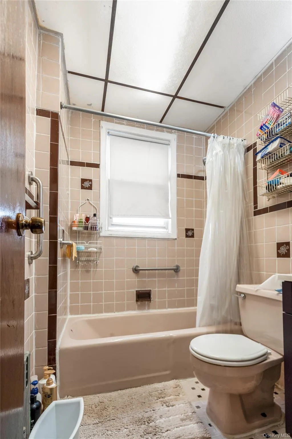 Bathroom featuring shower / bath combination with curtain, tile walls, and tile patterned flooring Bathroom featuring shower / bath combination with curtain, tile walls, and tile patterned flooring