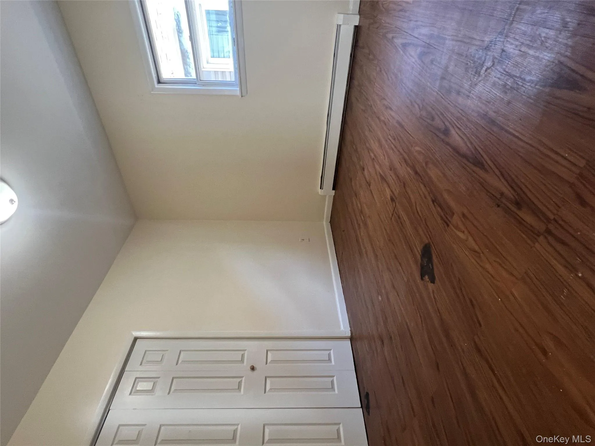 Empty room with dark wood finished floors and a baseboard heating unit Empty room with dark wood finished floors and a baseboard heating unit
