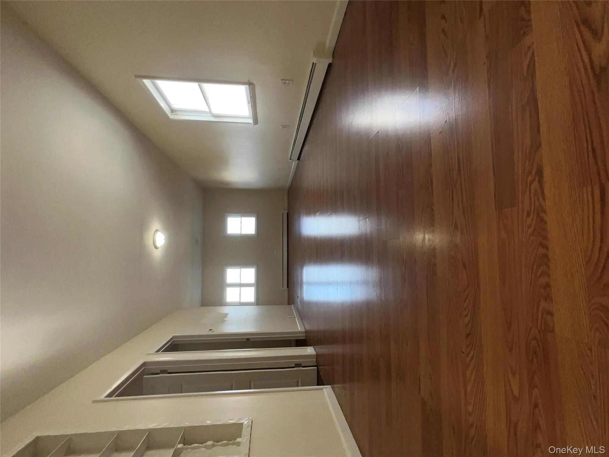 Unfurnished room featuring a baseboard heating unit, dark wood-style flooring, and plenty of natural light Unfurnished room featuring a baseboard heating unit, dark wood-style flooring, and plenty of natural light