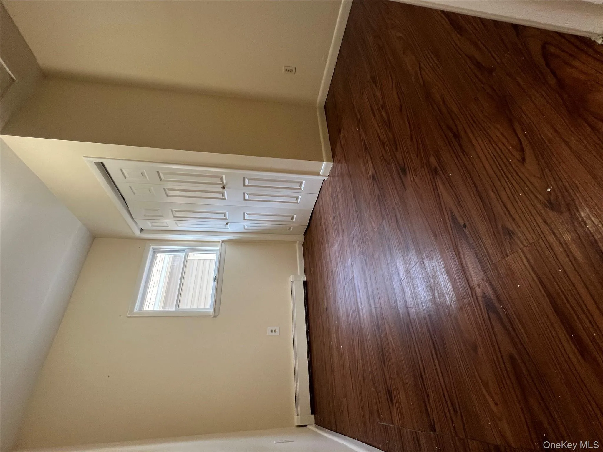 Unfurnished bedroom with dark wood-type flooring, a baseboard heating unit, and a closet Unfurnished bedroom with dark wood-type flooring, a baseboard heating unit, and a closet