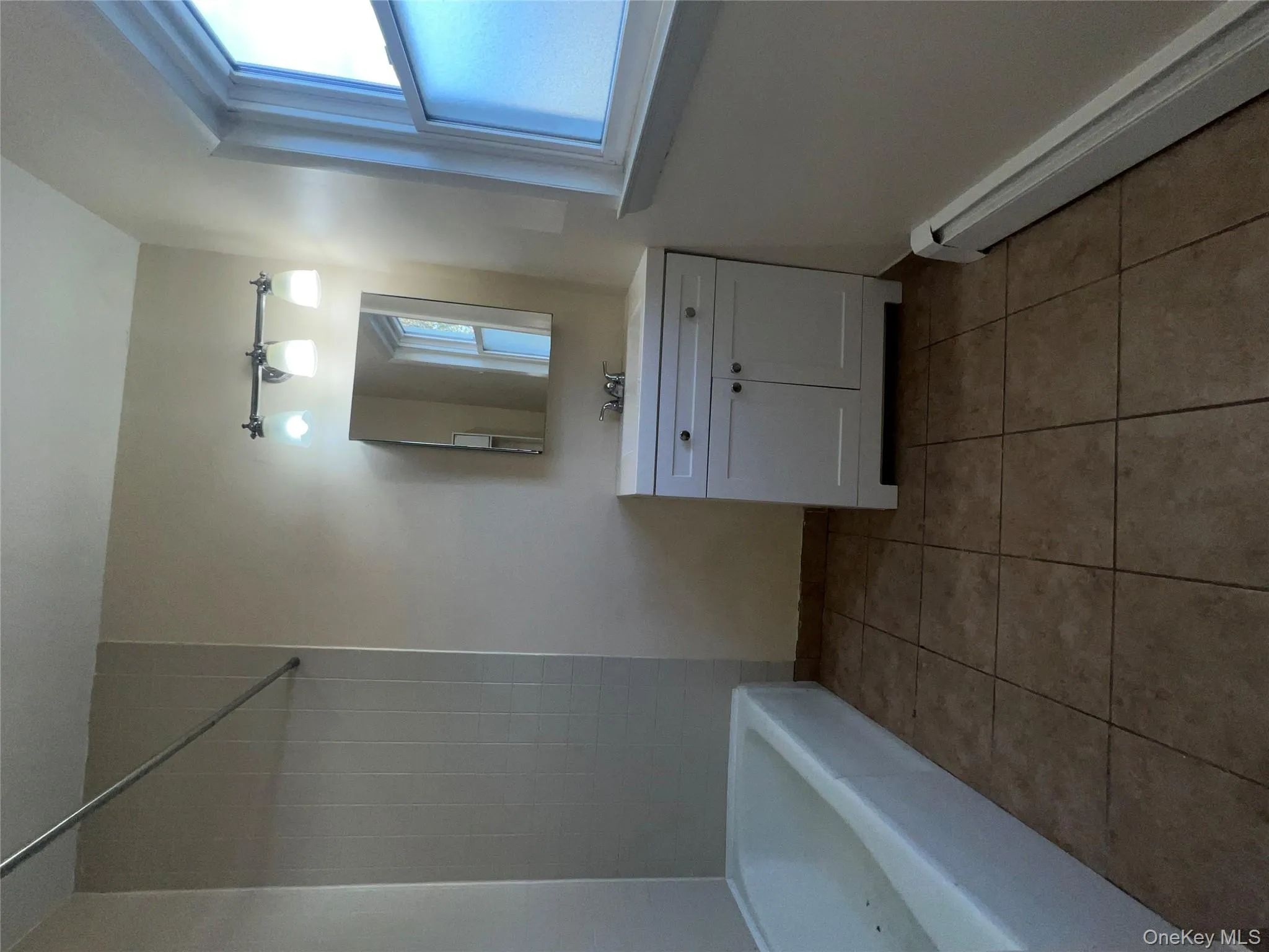 Bathroom featuring baseboard heating, vanity, light tile patterned flooring, and shower / bathtub combination Bathroom featuring baseboard heating, vanity, light tile patterned flooring, and shower / bathtub combination