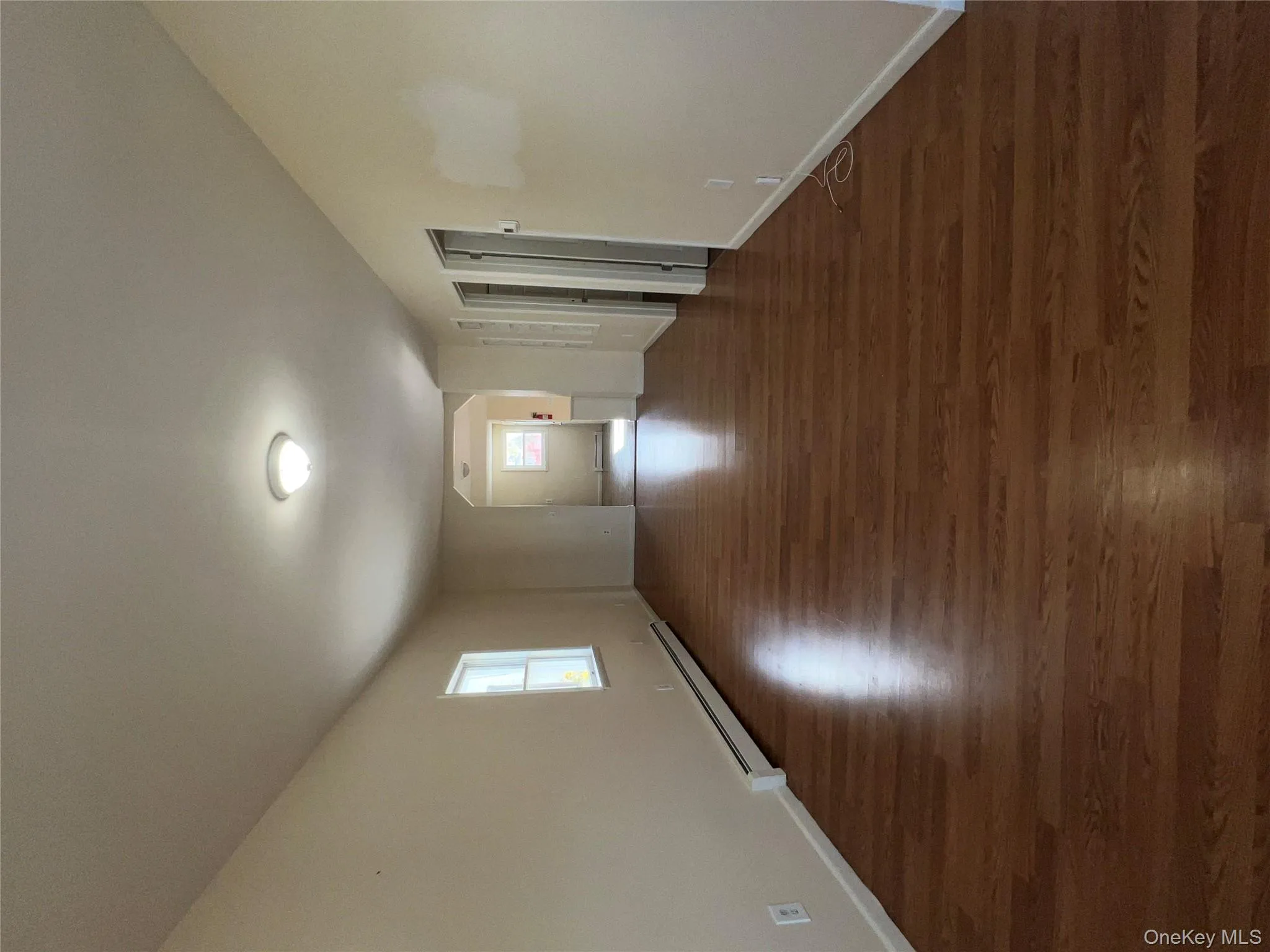 Spare room featuring a baseboard radiator, dark wood-type flooring, and arched walkways Spare room featuring a baseboard radiator, dark wood-type flooring, and arched walkways