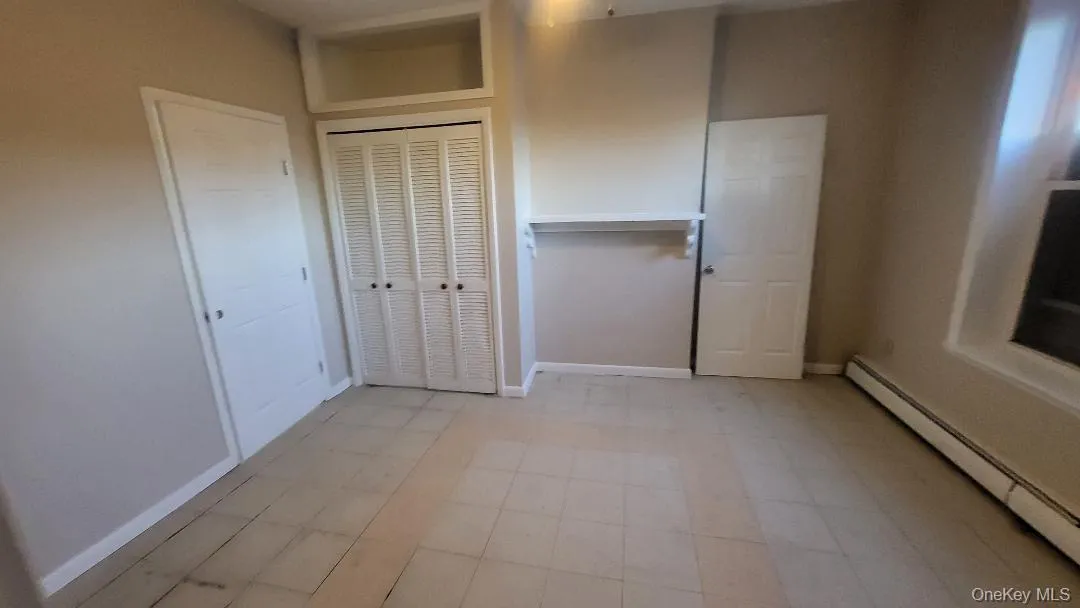 Unfurnished bedroom with a baseboard heating unit and baseboards Unfurnished bedroom with a baseboard heating unit and baseboards