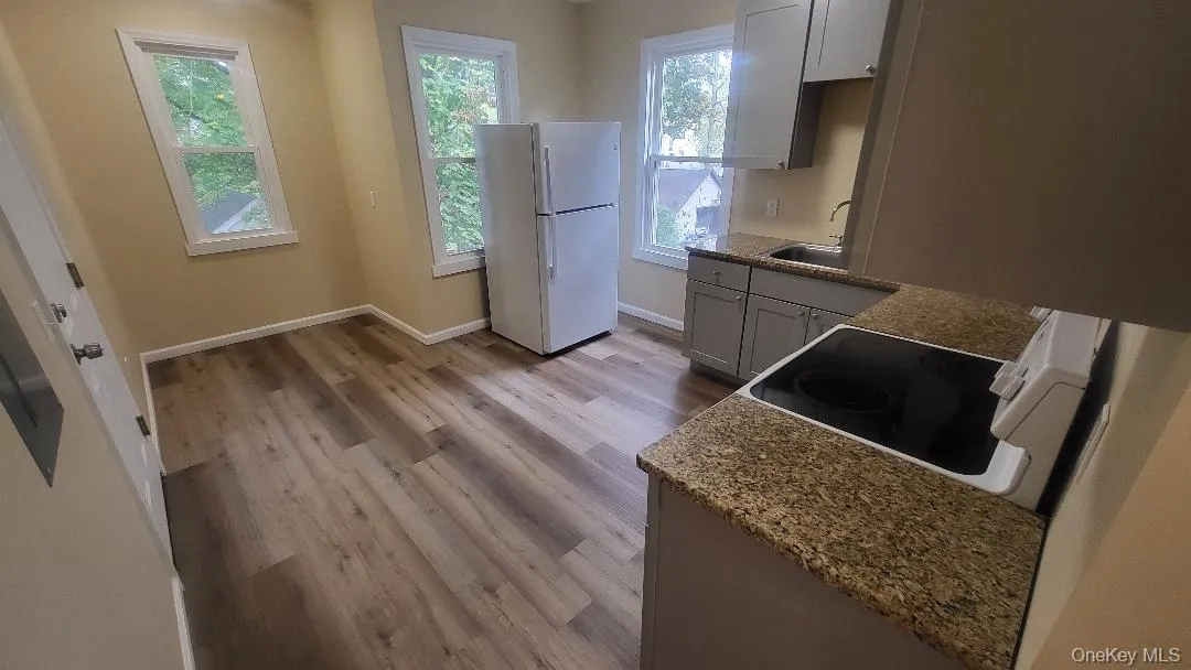Kitchen featuring white appliances, light stone counters, light wood-type flooring, and gray cabinets Kitchen featuring white appliances, light stone counters, light wood-type flooring, and gray cabinets