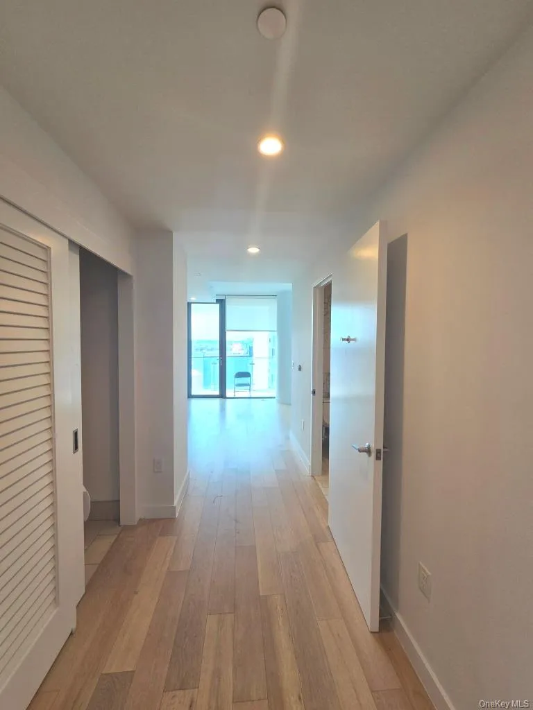 Hall featuring light wood finished floors, recessed lighting, and expansive windows Hall featuring light wood finished floors, recessed lighting, and expansive windows