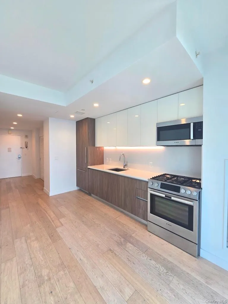 Kitchen featuring modern cabinets, white cabinetry, light countertops, stainless steel appliances, and recessed lighting Kitchen featuring modern cabinets, white cabinetry, light countertops, stainless steel appliances, and recessed lighting