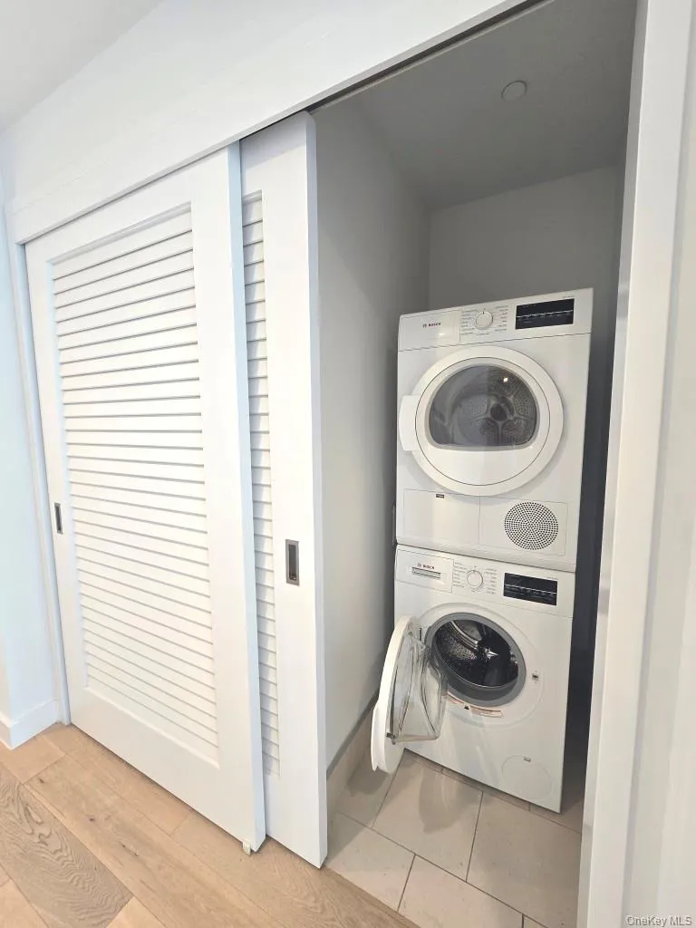 Laundry room with light wood finished floors and stacked washer / drying machine Laundry room with light wood finished floors and stacked washer / drying machine