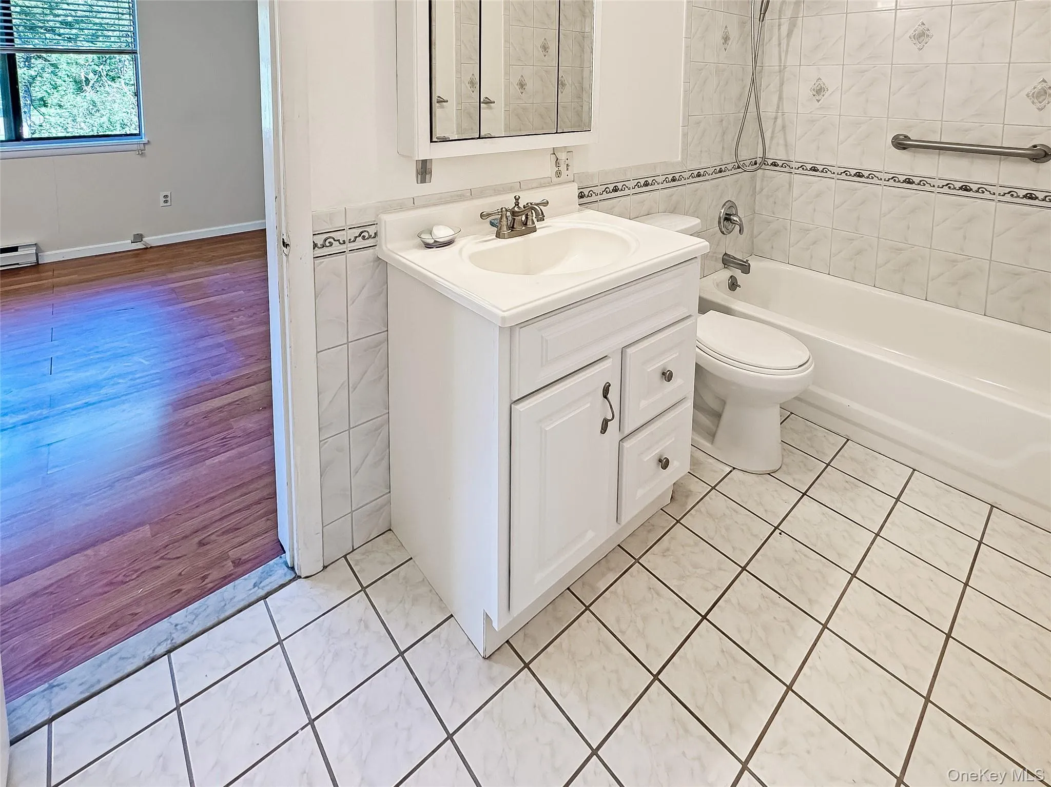 Bathroom with vanity, tile walls, bathing tub / shower combination, and light tile patterned flooring Bathroom with vanity, tile walls, bathing tub / shower combination, and light tile patterned flooring