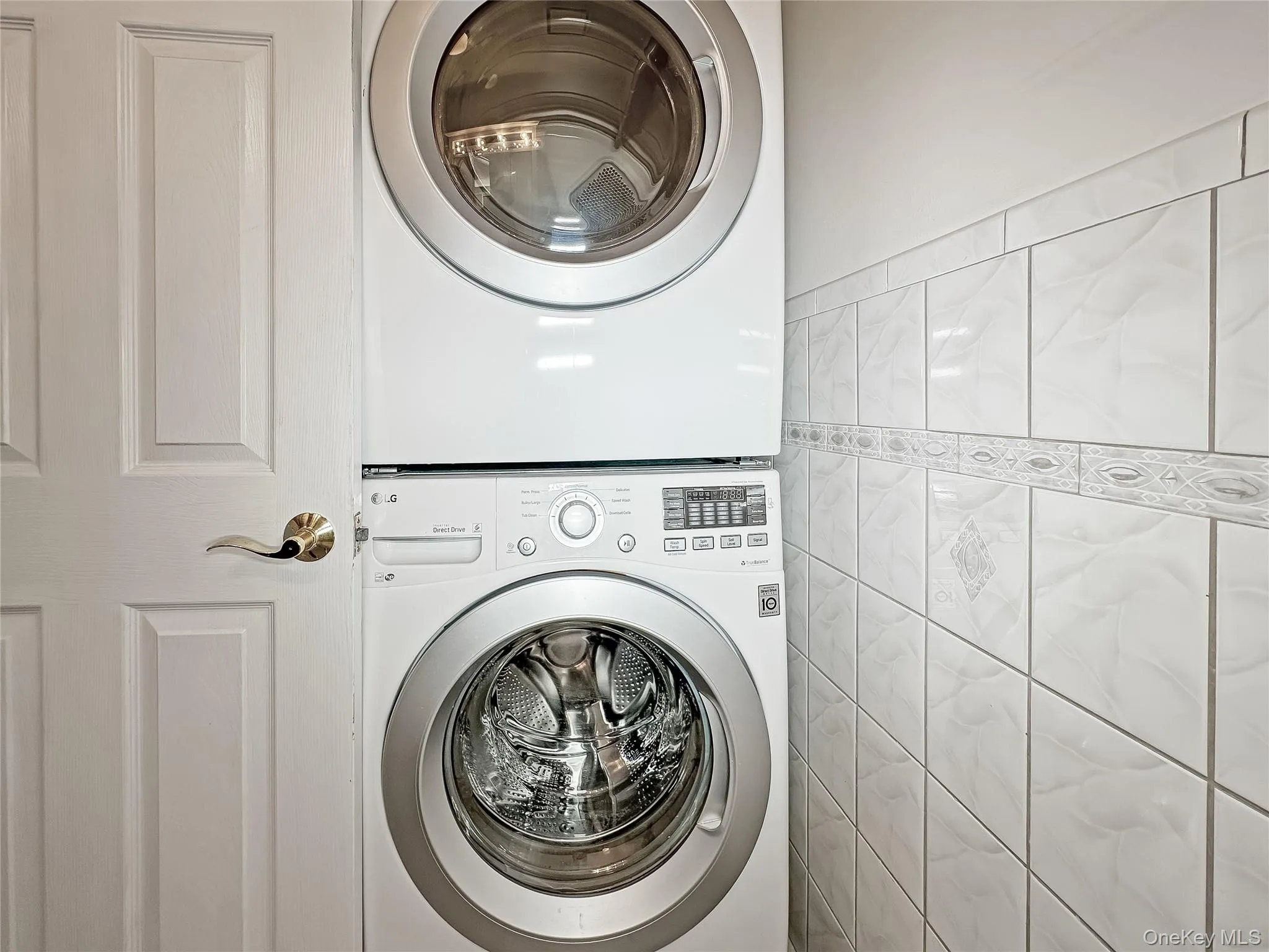 Washroom with estacked washer and dryer and tile walls Washroom with estacked washer and dryer and tile walls