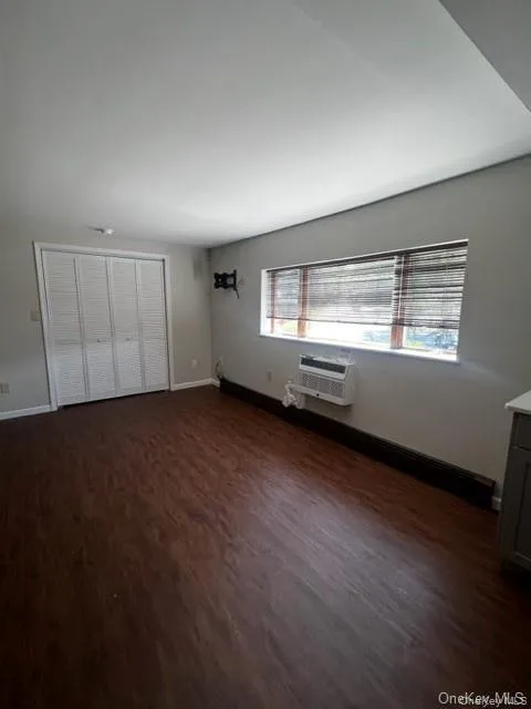 Unfurnished bedroom featuring dark wood finished floors and baseboards Unfurnished bedroom featuring dark wood finished floors and baseboards