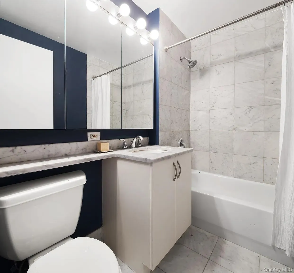 Bathroom featuring vanity, shower / bath combo with shower curtain, and light tile patterned floors Bathroom featuring vanity, shower / bath combo with shower curtain, and light tile patterned floors