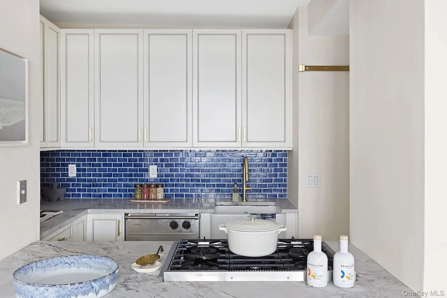 Kitchen with white cabinets, light stone counters, decorative backsplash, and dishwasher Kitchen with white cabinets, light stone counters, decorative backsplash, and dishwasher