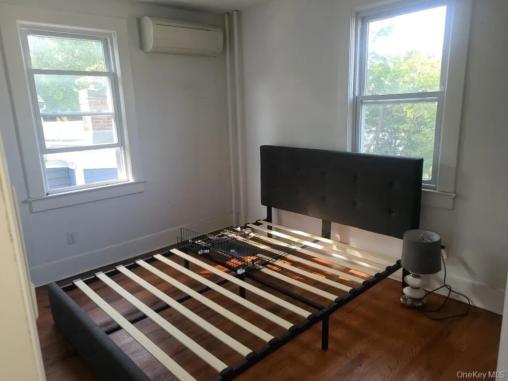 Bedroom featuring a wall mounted AC and wood finished floors Bedroom featuring a wall mounted AC and wood finished floors