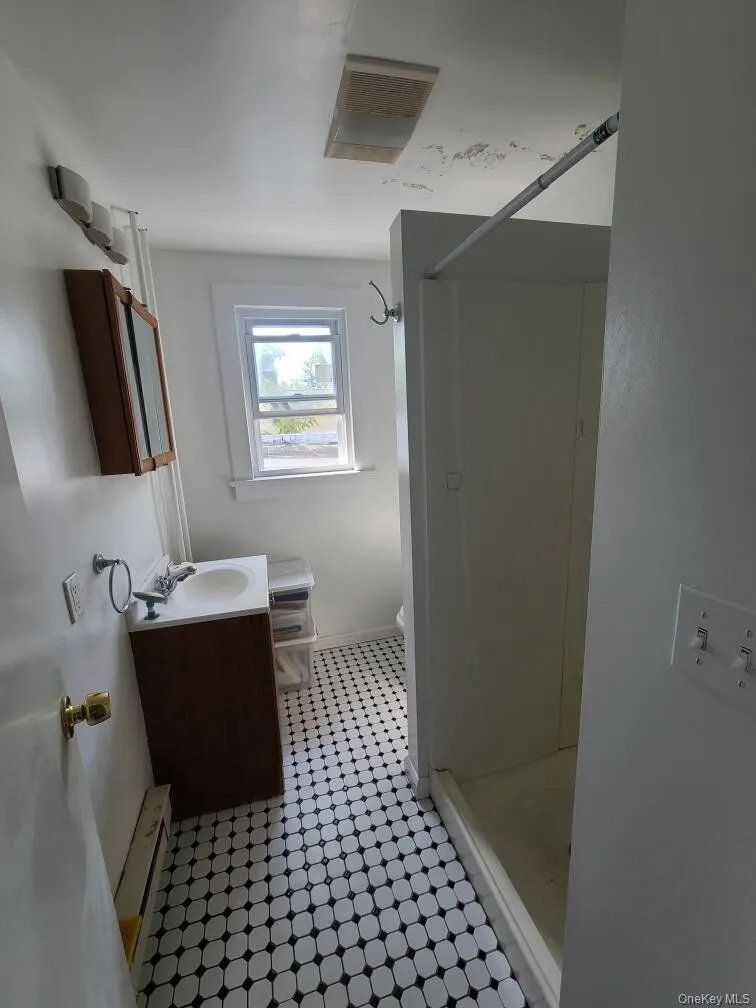 Full bath with vanity, a shower stall, and baseboard heating Full bath with vanity, a shower stall, and baseboard heating