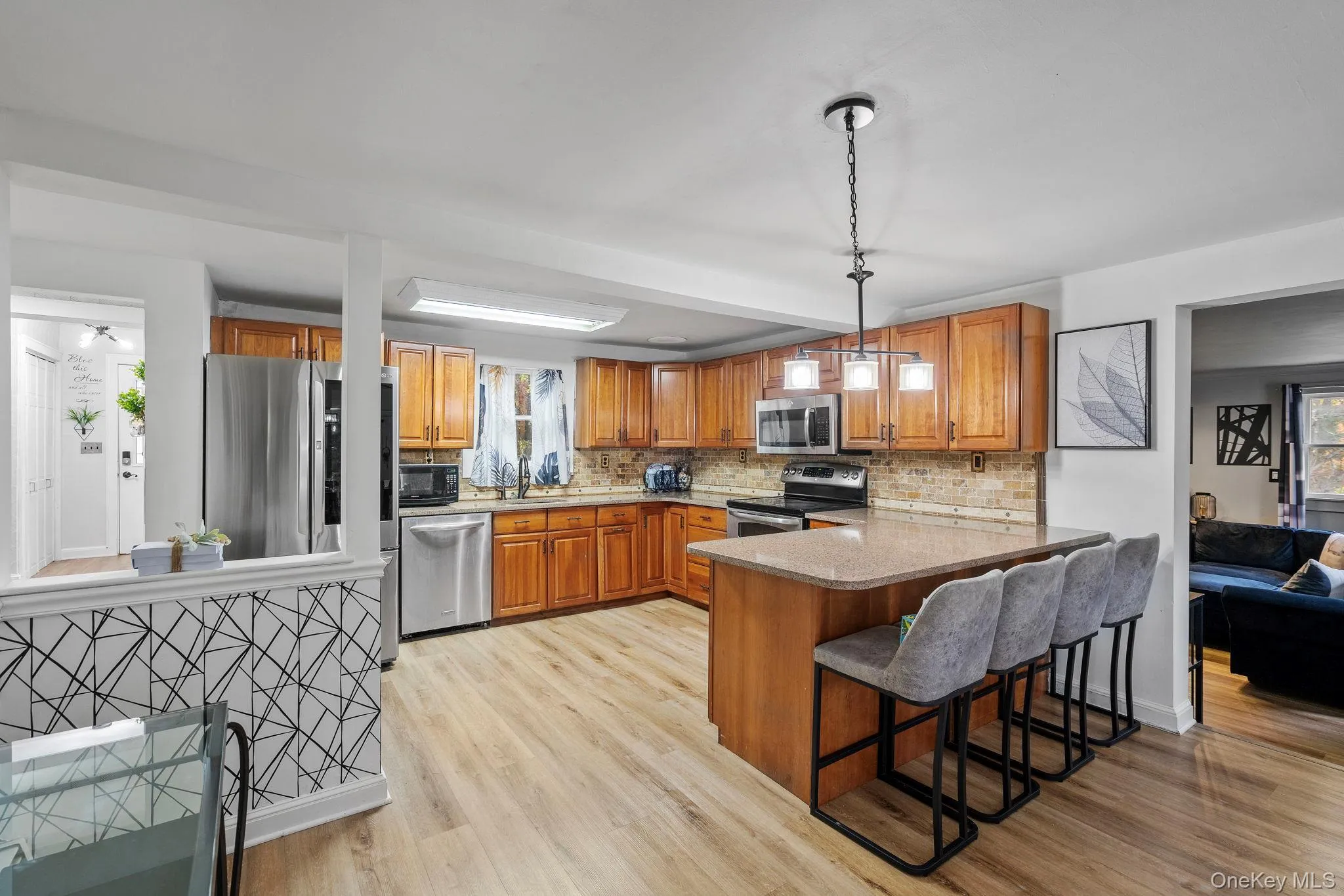 Kitchen featuring brown cabinets, hanging light fixtures, stainless steel appliances, and healthy amount of natural light Kitchen featuring brown cabinets, hanging light fixtures, stainless steel appliances, and healthy amount of natural light