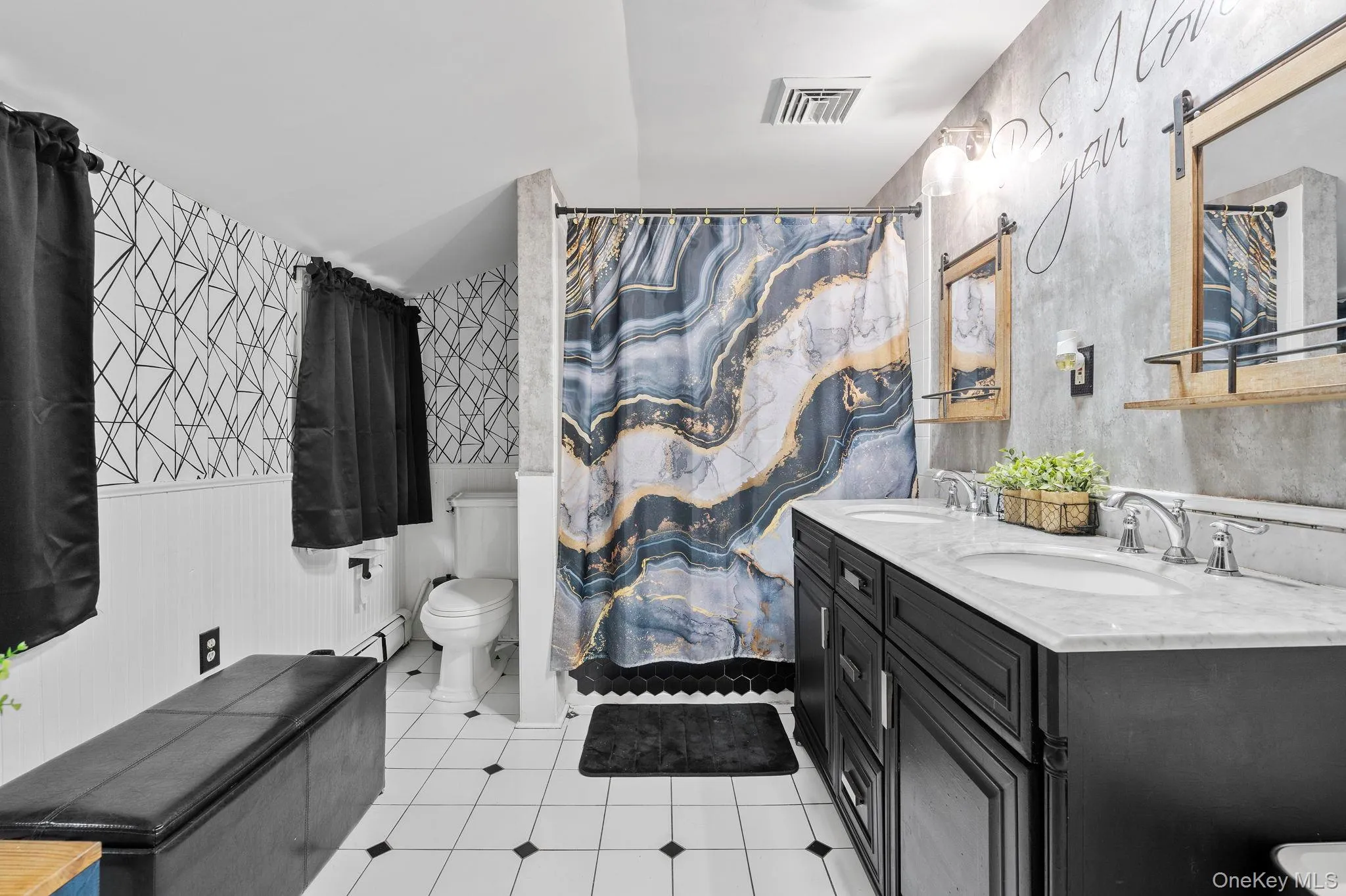 Full bath with double vanity, curtained shower, light tile patterned flooring, a baseboard heating unit, and wainscoting Full bath with double vanity, curtained shower, light tile patterned flooring, a baseboard heating unit, and wainscoting
