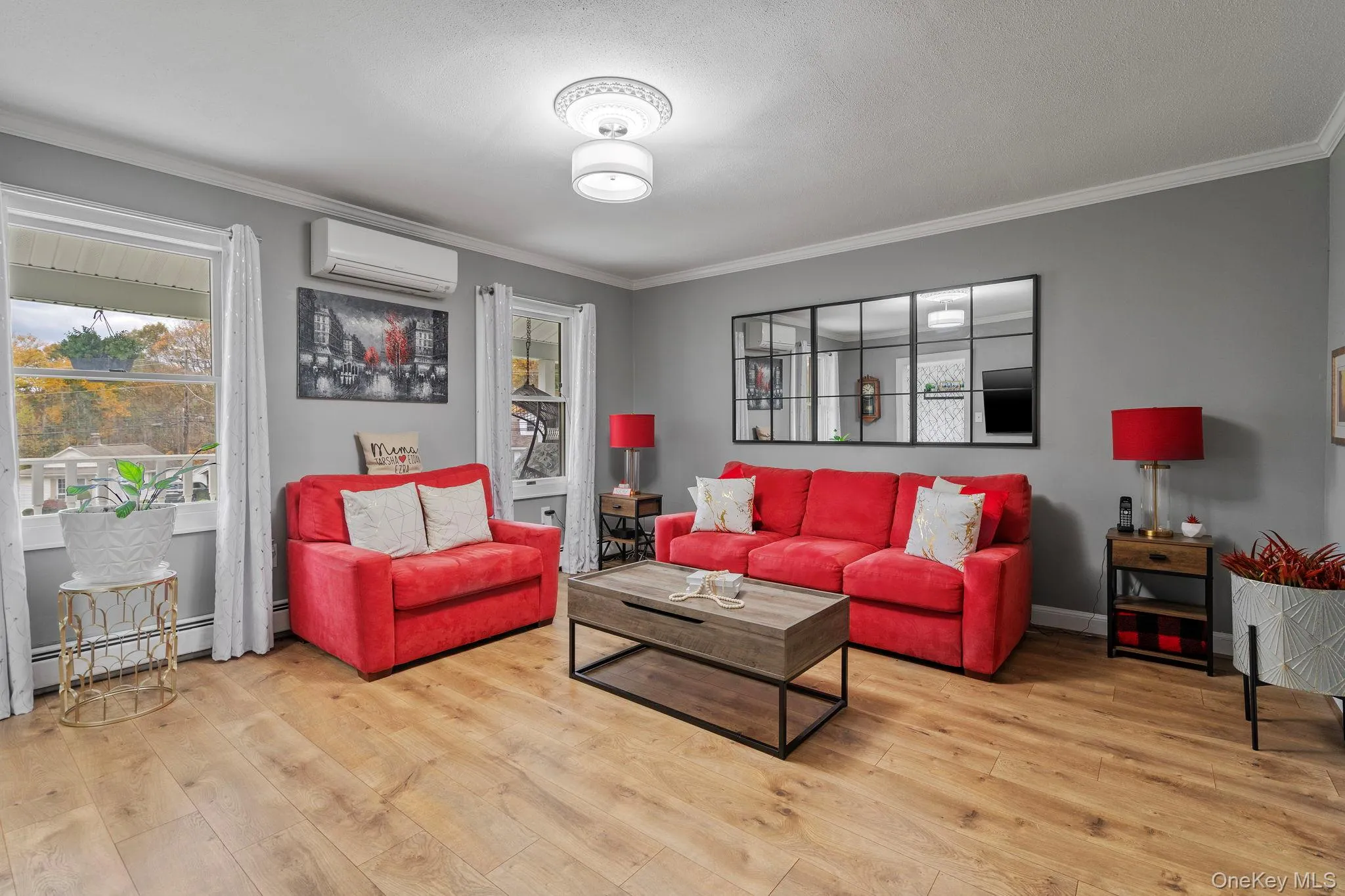 Living room with ornamental molding, light wood-style floors, and a wall mounted AC Living room with ornamental molding, light wood-style floors, and a wall mounted AC