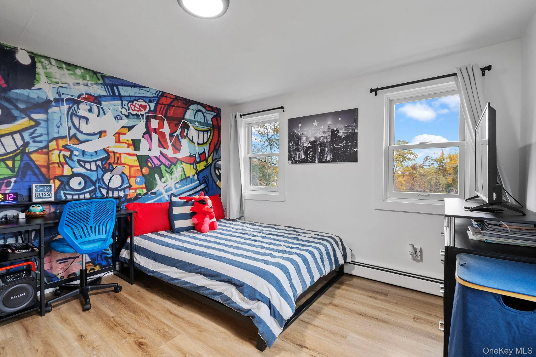 Bedroom with light wood-style flooring, baseboard heating, and an office area Bedroom with light wood-style flooring, baseboard heating, and an office area