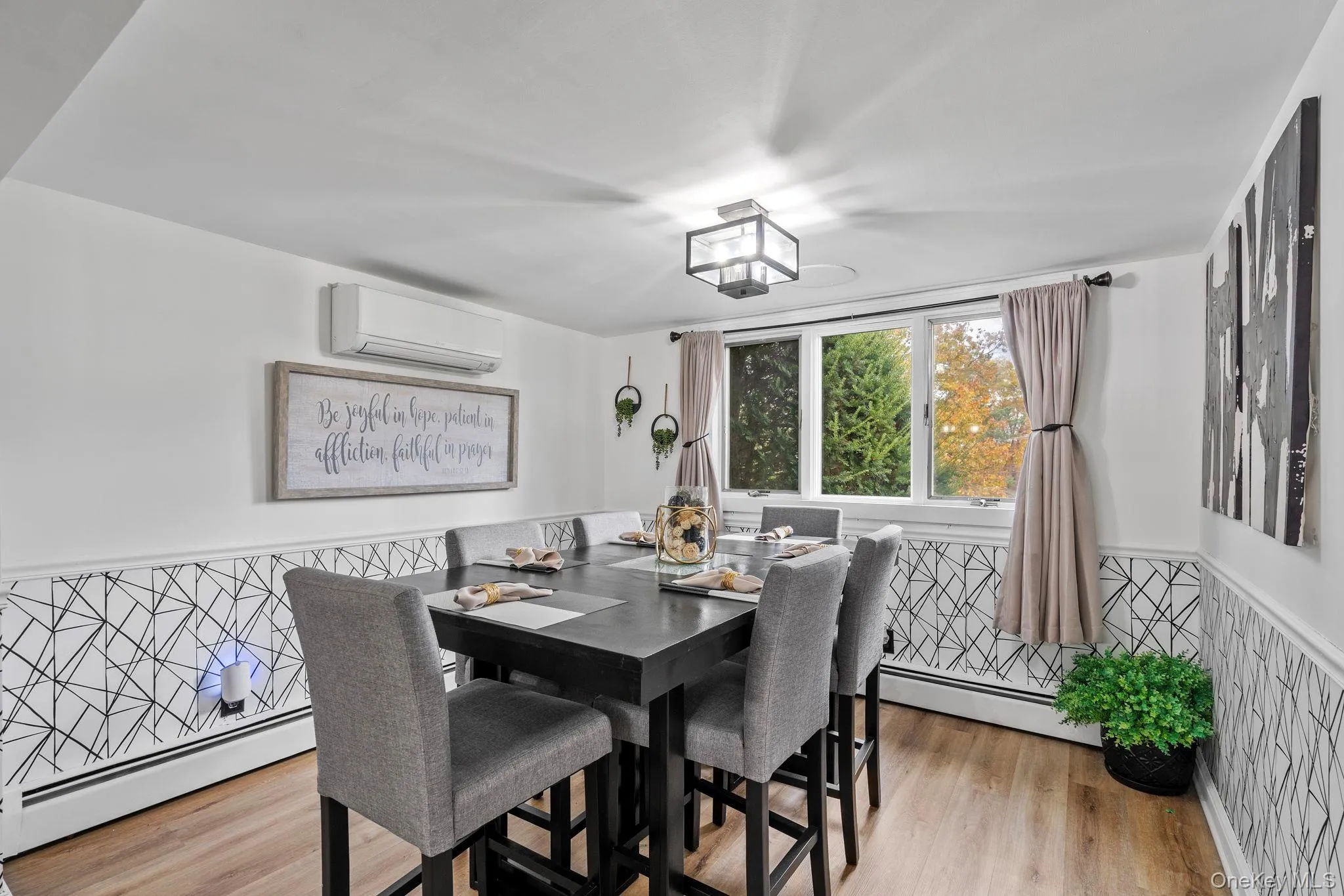 Dining area featuring wainscoting, baseboard heating, light wood-style floors, and a wall unit AC Dining area featuring wainscoting, baseboard heating, light wood-style floors, and a wall unit AC