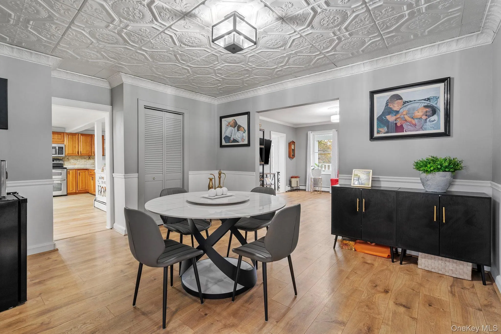 Dining space featuring light wood-style floors, ornamental molding, an ornate ceiling, and a wainscoted wall Dining space featuring light wood-style floors, ornamental molding, an ornate ceiling, and a wainscoted wall
