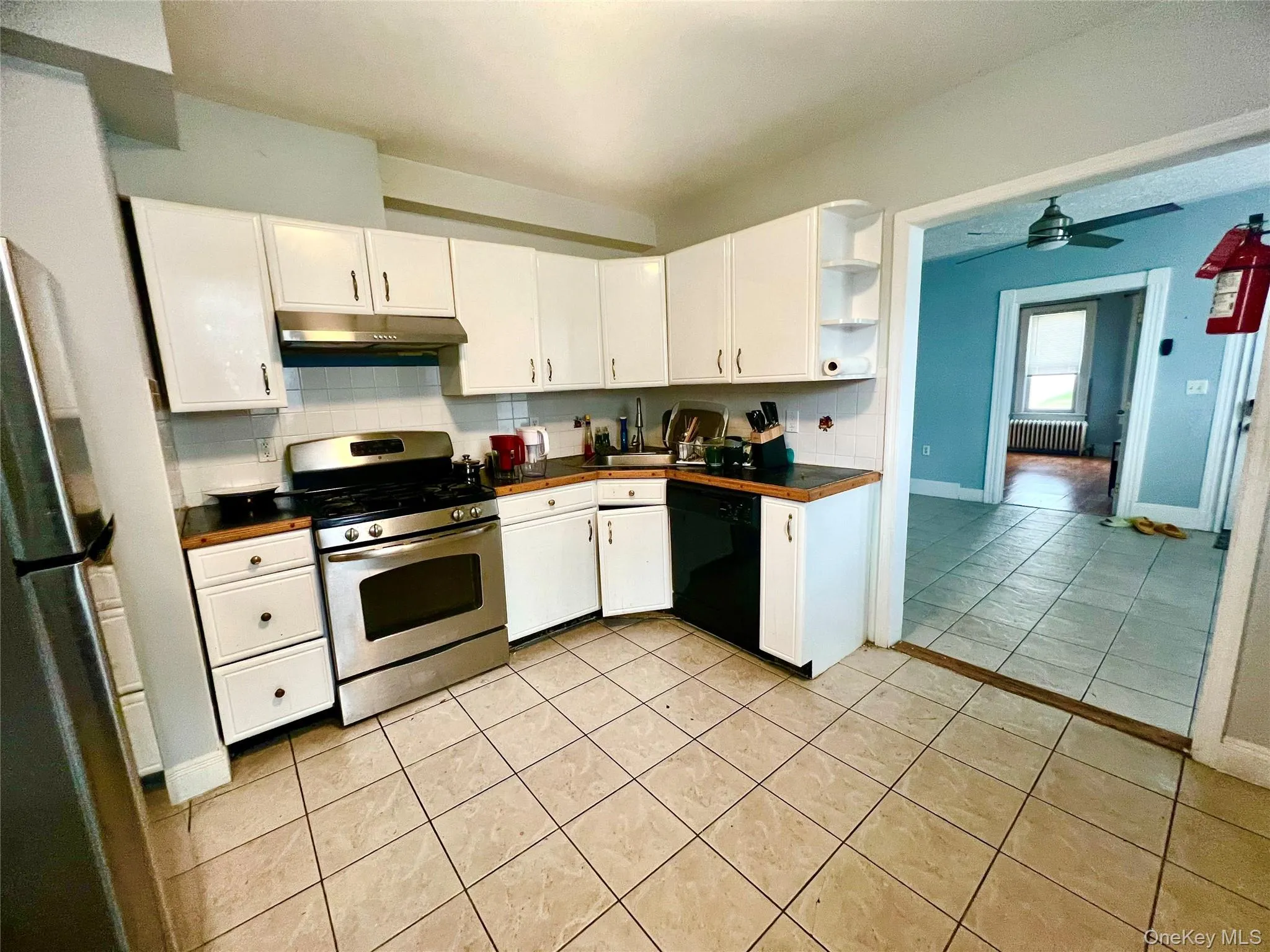 Kitchen featuring decorative backsplash, white cabinets, light tile patterned floors, and appliances with stainless steel finishes Kitchen featuring decorative backsplash, white cabinets, light tile patterned floors, and appliances with stainless steel finishes