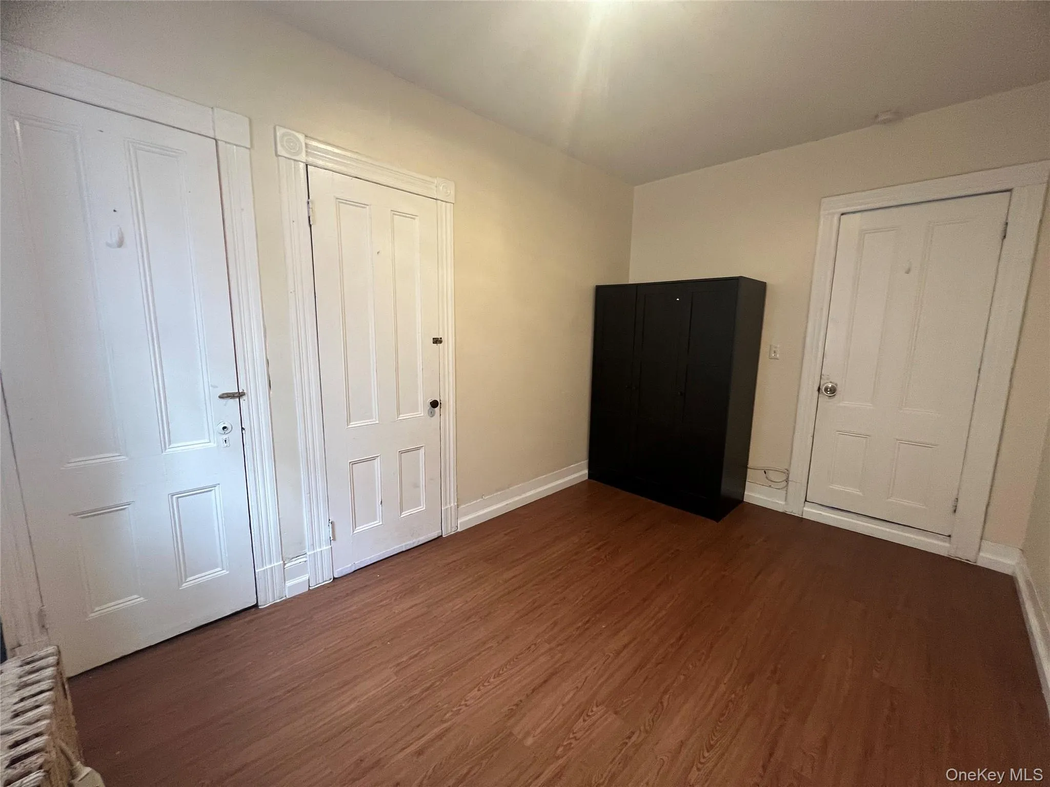 Unfurnished bedroom featuring dark wood-style flooring and baseboards Unfurnished bedroom featuring dark wood-style flooring and baseboards