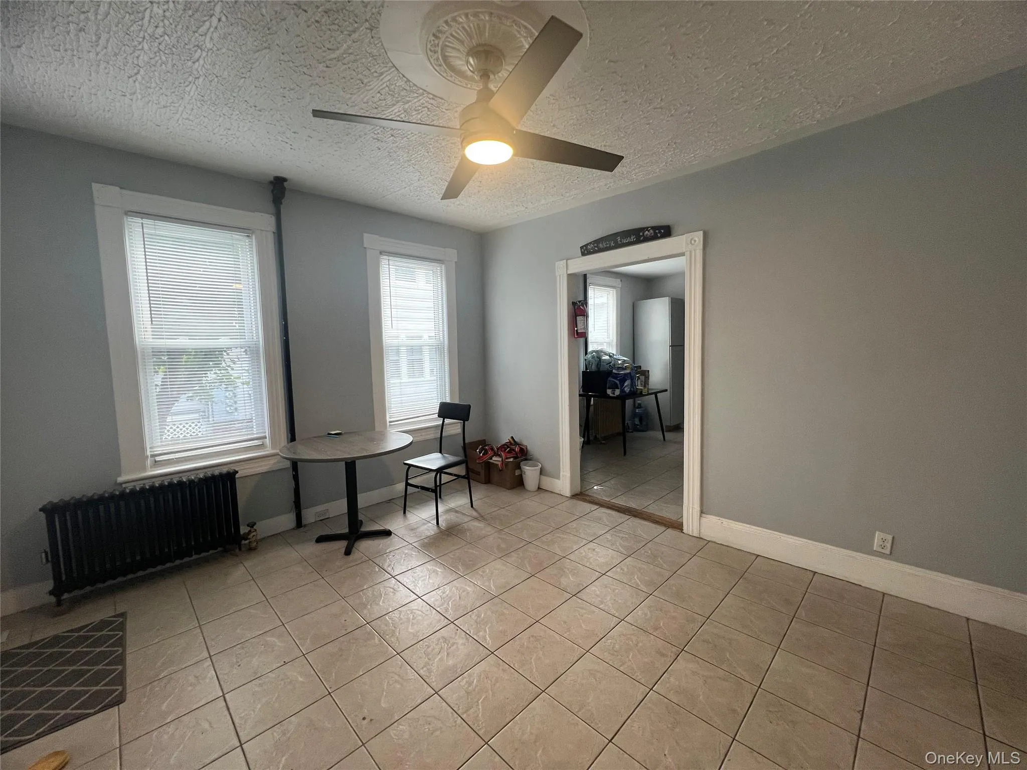 Office space featuring radiator, a textured ceiling, light tile patterned floors, and ceiling fan Office space featuring radiator, a textured ceiling, light tile patterned floors, and ceiling fan