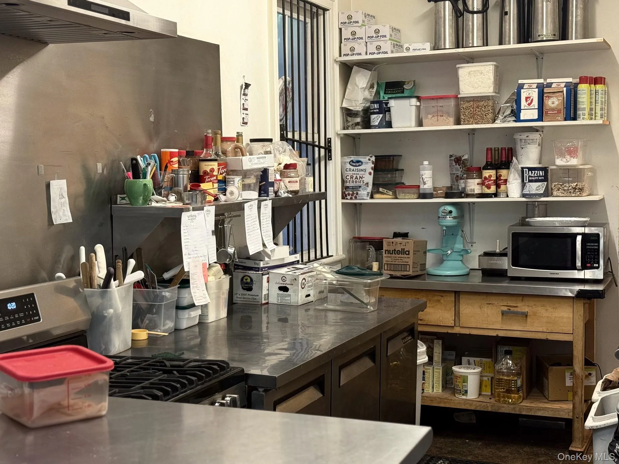 Kitchen featuring appliances with stainless steel finishes, under cabinet range hood, and stainless steel counters Kitchen featuring appliances with stainless steel finishes, under cabinet range hood, and stainless steel counters