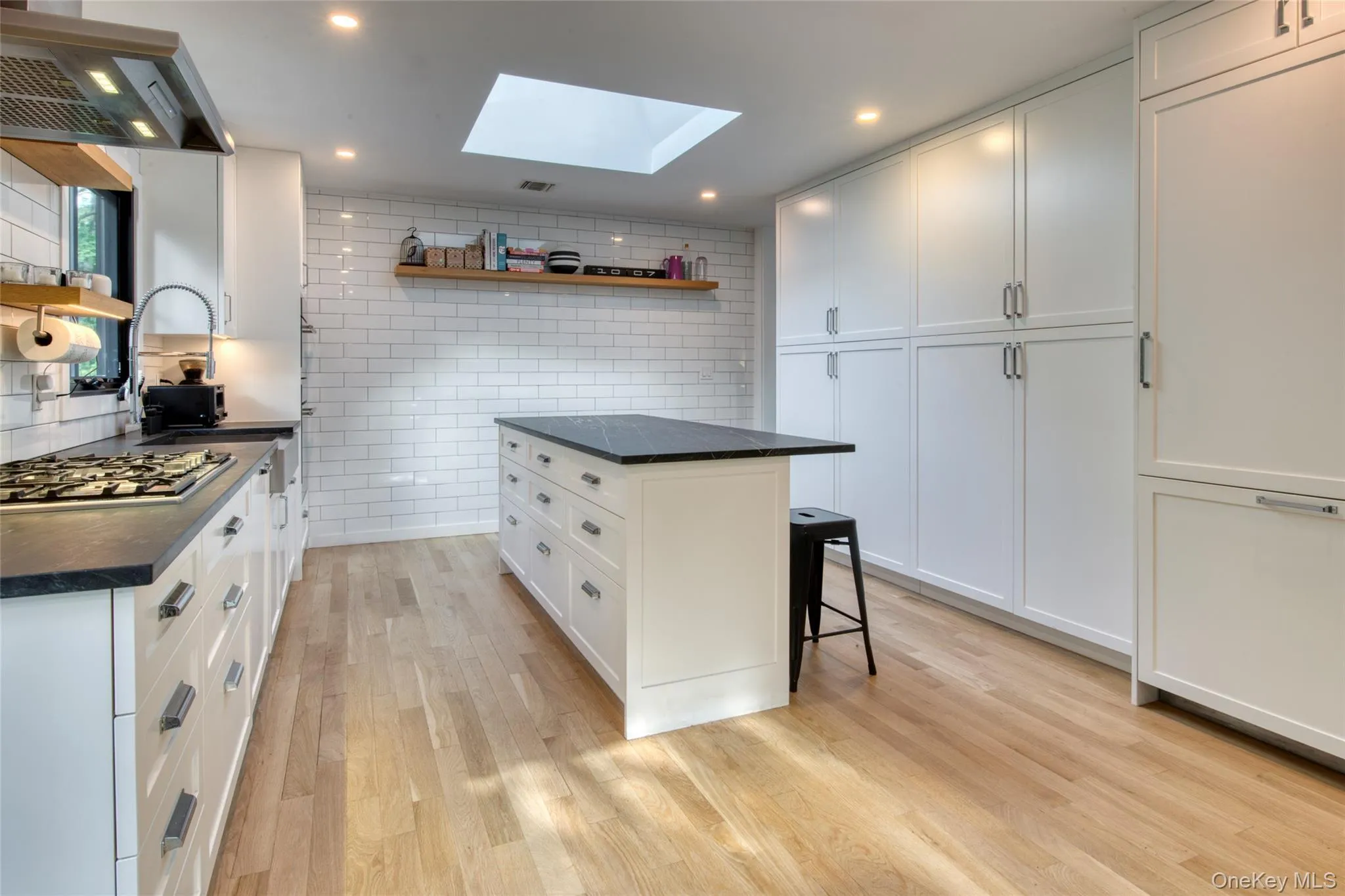 Kitchen with open shelves, a kitchen breakfast bar, exhaust hood, tasteful backsplash, and white cabinets Kitchen with open shelves, a kitchen breakfast bar, exhaust hood, tasteful backsplash, and white cabinets