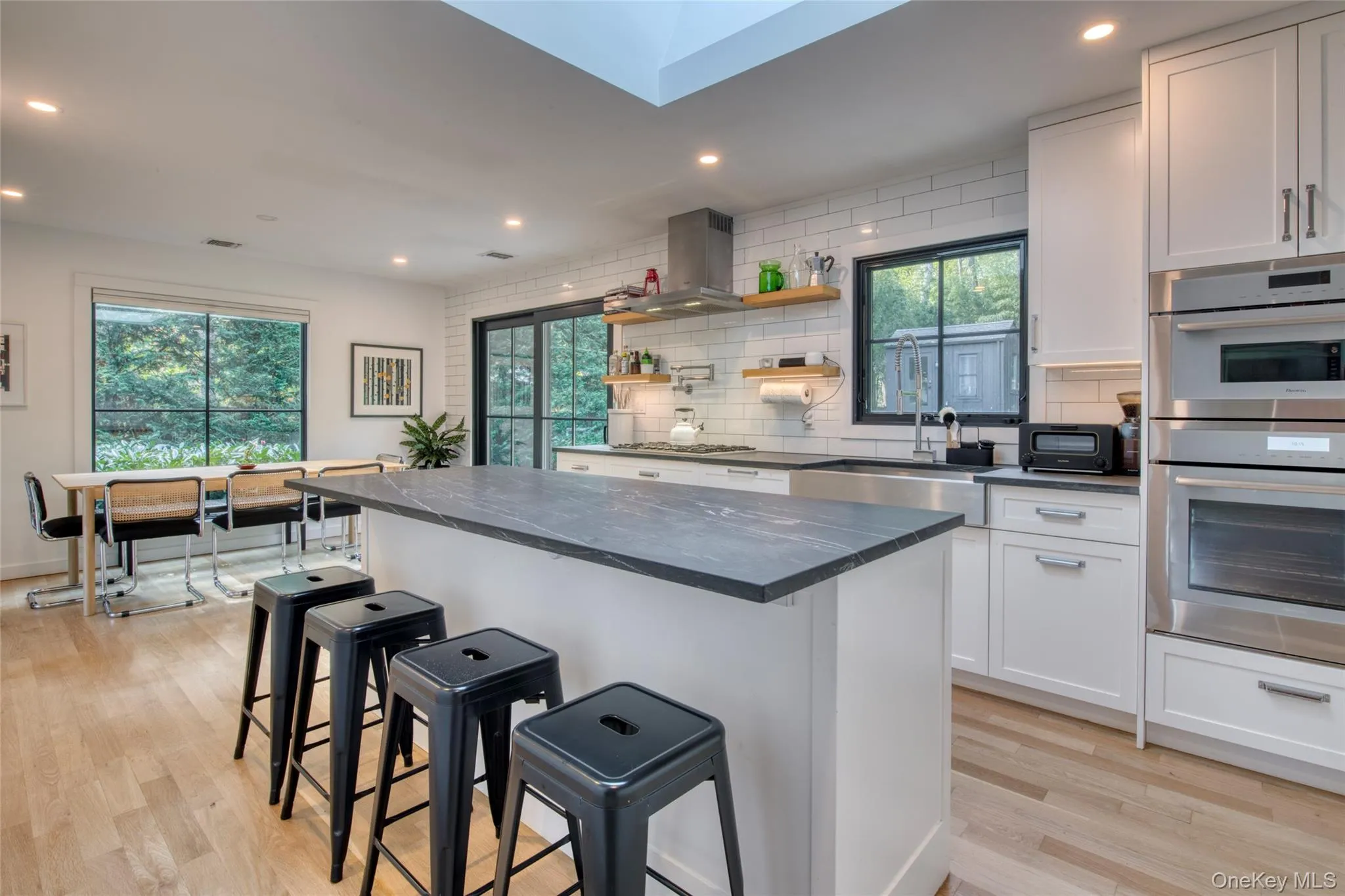 Kitchen featuring a breakfast bar, open shelves, backsplash, recessed lighting, and appliances with stainless steel finishes Kitchen featuring a breakfast bar, open shelves, backsplash, recessed lighting, and appliances with stainless steel finishes