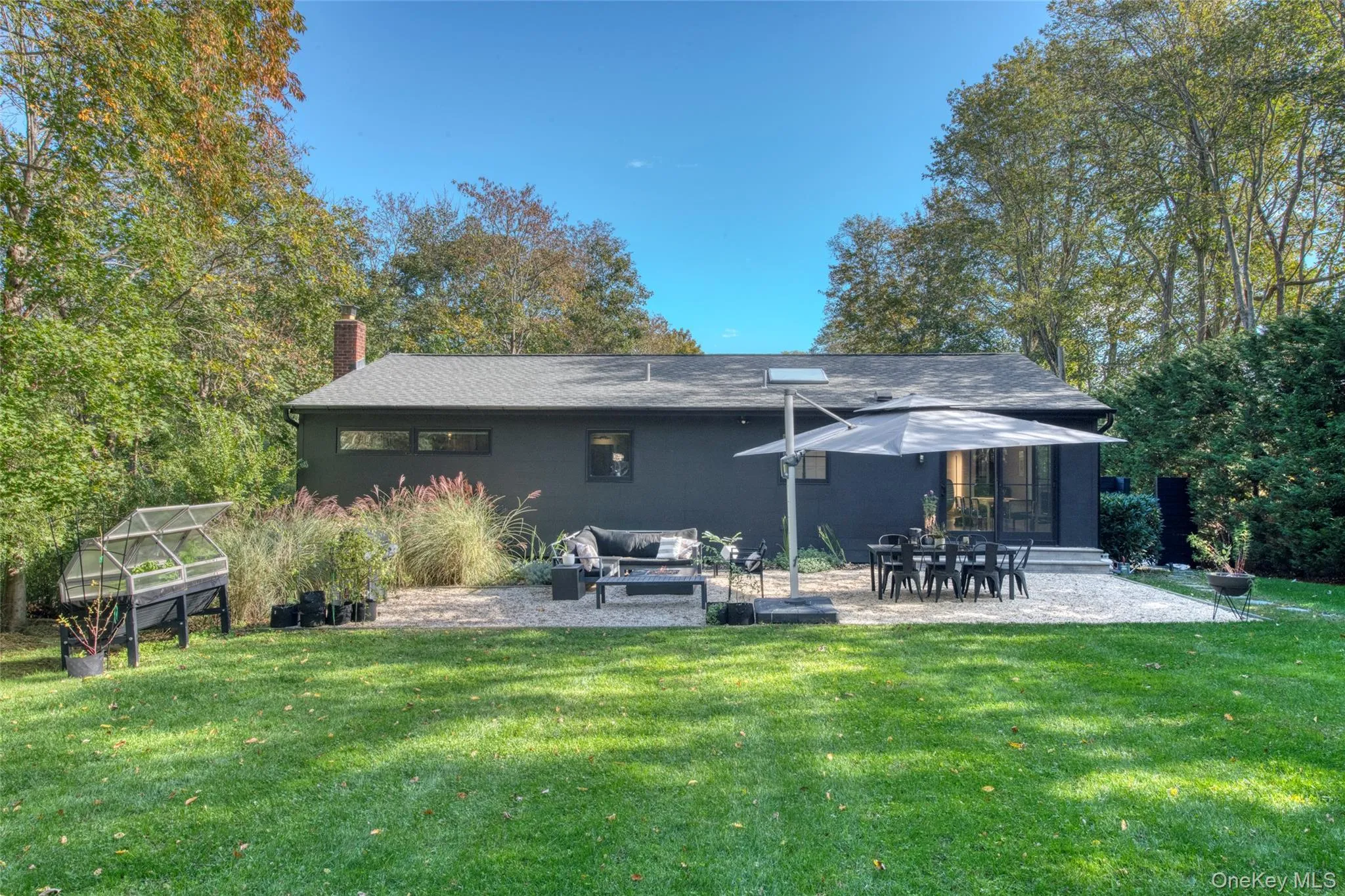 Rear view of house with a chimney, an exterior structure, a patio area, a yard, and an outdoor structure Rear view of house with a chimney, an exterior structure, a patio area, a yard, and an outdoor structure