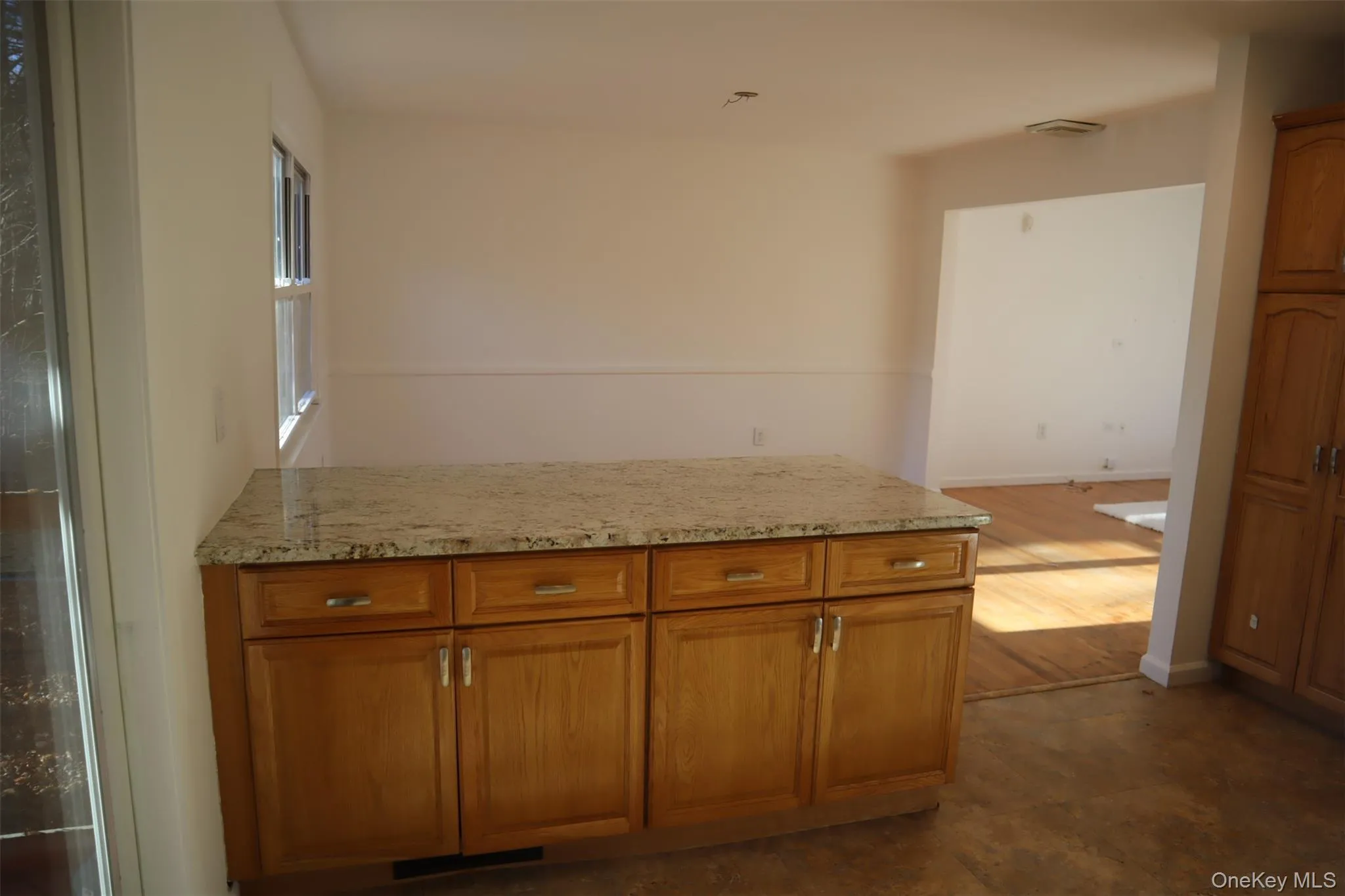 Kitchen featuring brown cabinetry, light stone counters, and a peninsula Kitchen featuring brown cabinetry, light stone counters, and a peninsula