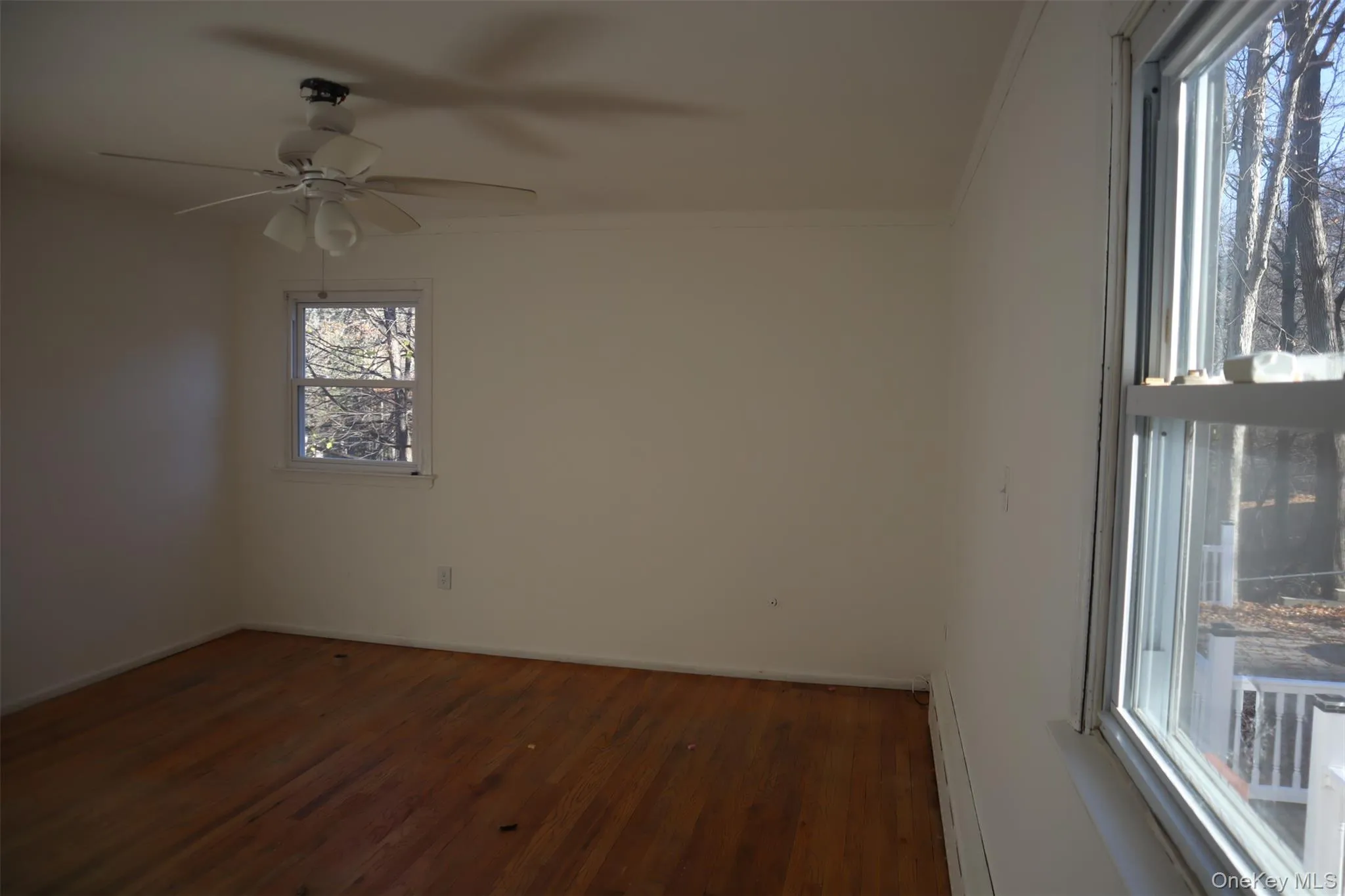 Unfurnished room featuring dark wood finished floors, crown molding, baseboard heating, and ceiling fan Unfurnished room featuring dark wood finished floors, crown molding, baseboard heating, and ceiling fan