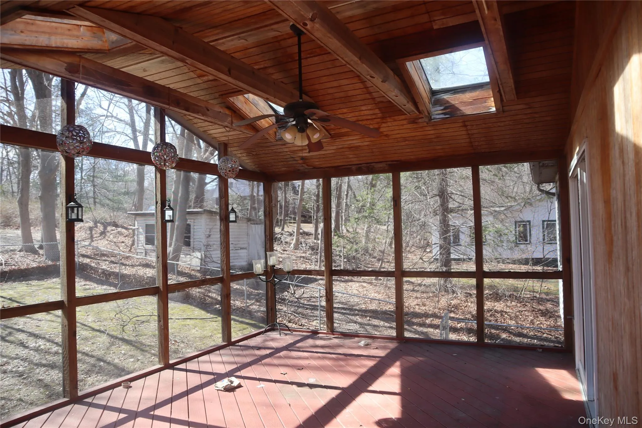 Unfurnished sunroom with ceiling fan, a skylight, a wooden deck, and plenty of natural light Unfurnished sunroom with ceiling fan, a skylight, a wooden deck, and plenty of natural light
