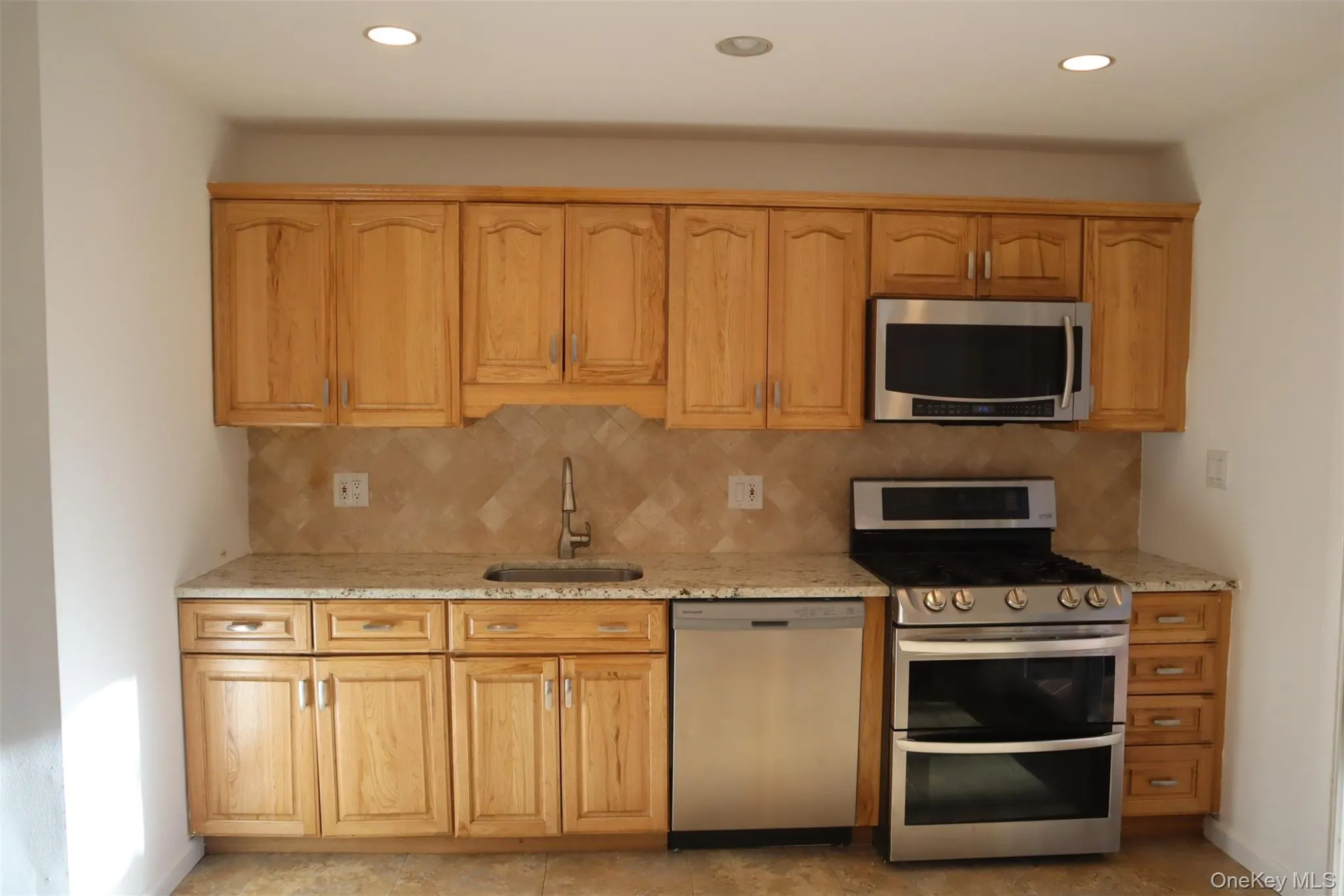 Kitchen with stainless steel appliances, light stone countertops, tasteful backsplash, and recessed lighting Kitchen with stainless steel appliances, light stone countertops, tasteful backsplash, and recessed lighting