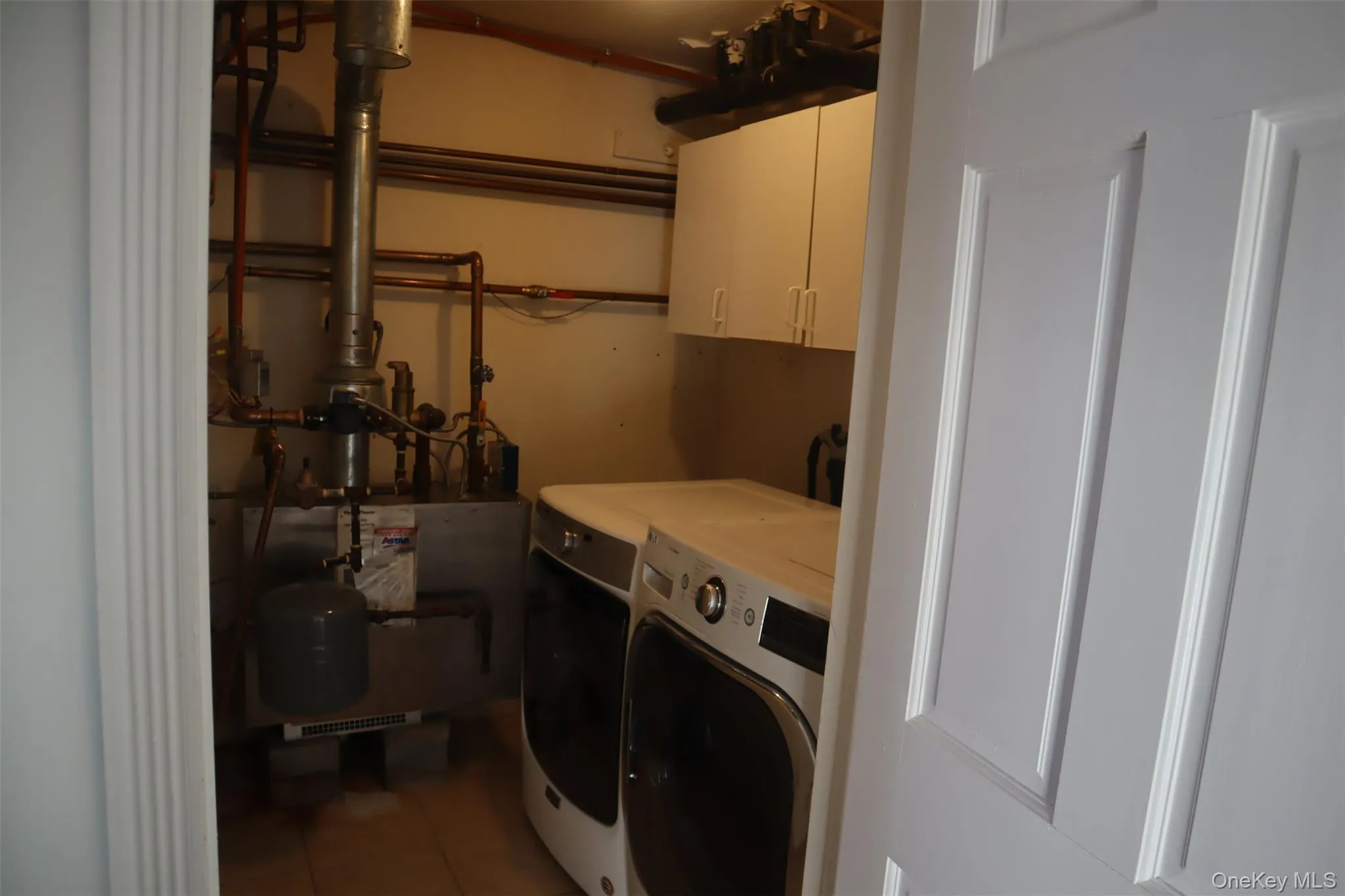 Laundry area featuring cabinet space, light tile patterned flooring, and washing machine and dryer Laundry area featuring cabinet space, light tile patterned flooring, and washing machine and dryer