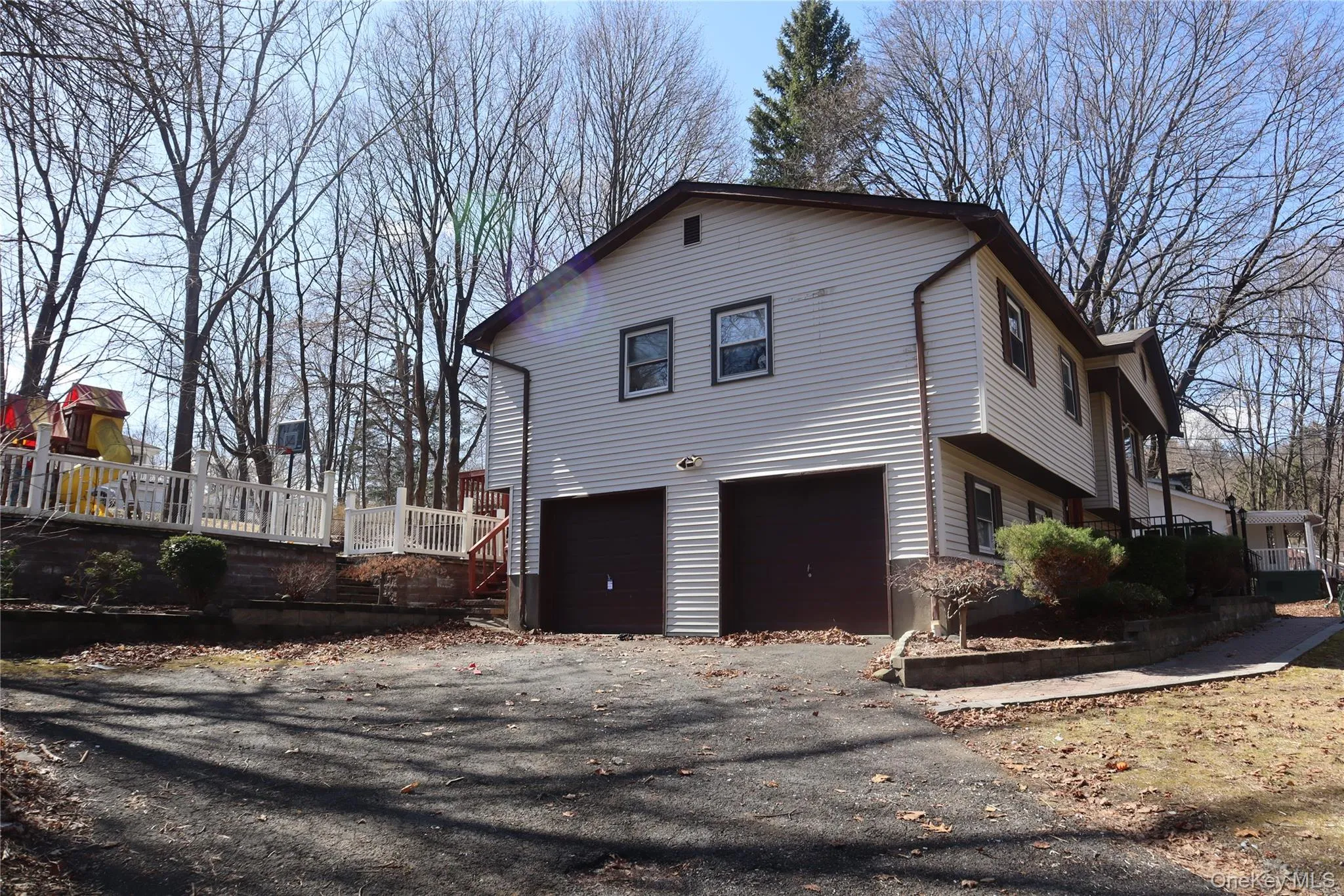 View of home's exterior featuring a wooden deck, a garage, and asphalt driveway View of home's exterior featuring a wooden deck, a garage, and asphalt driveway
