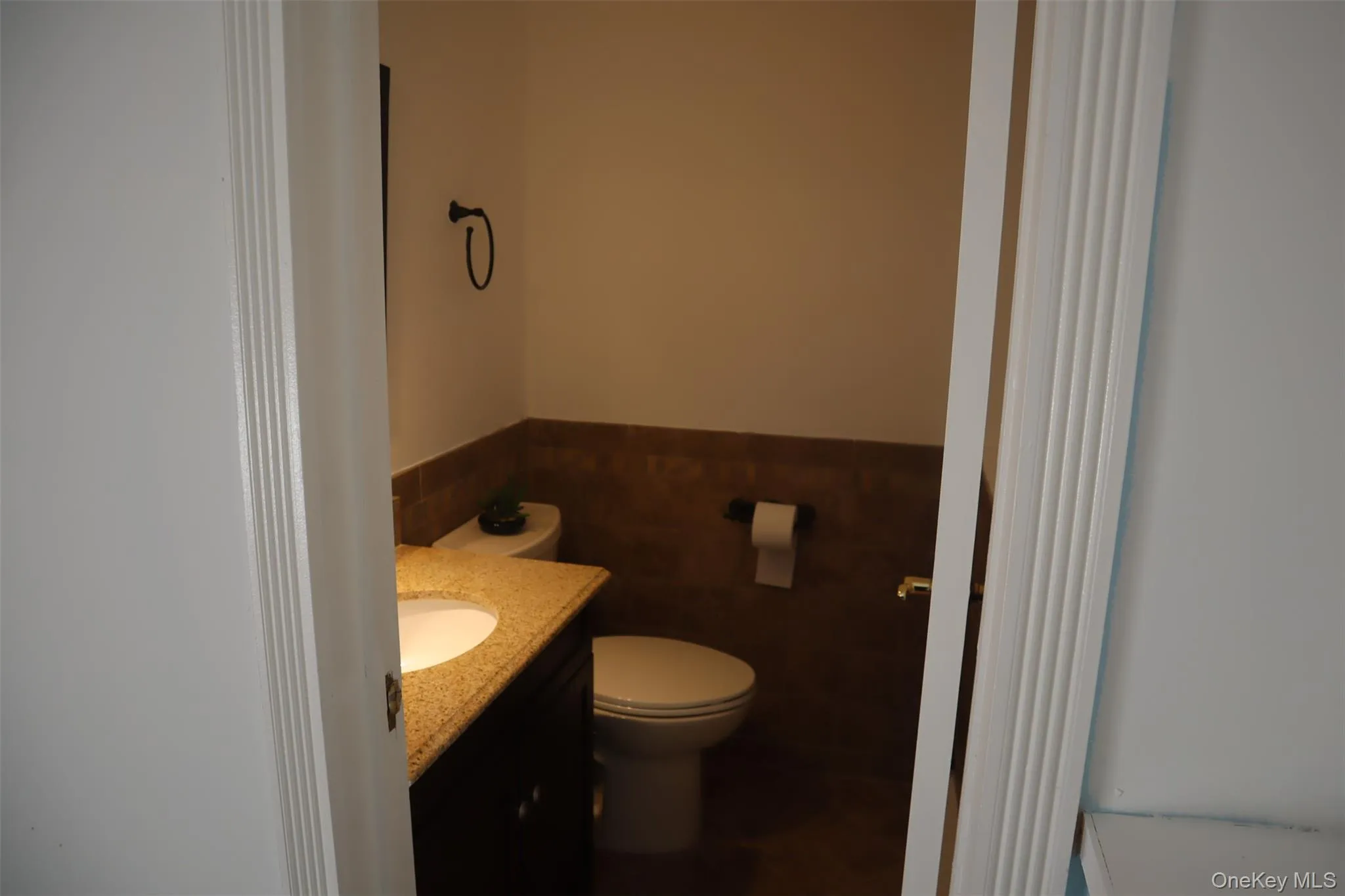 Half bath with vanity, a wainscoted wall, and tile walls Half bath with vanity, a wainscoted wall, and tile walls