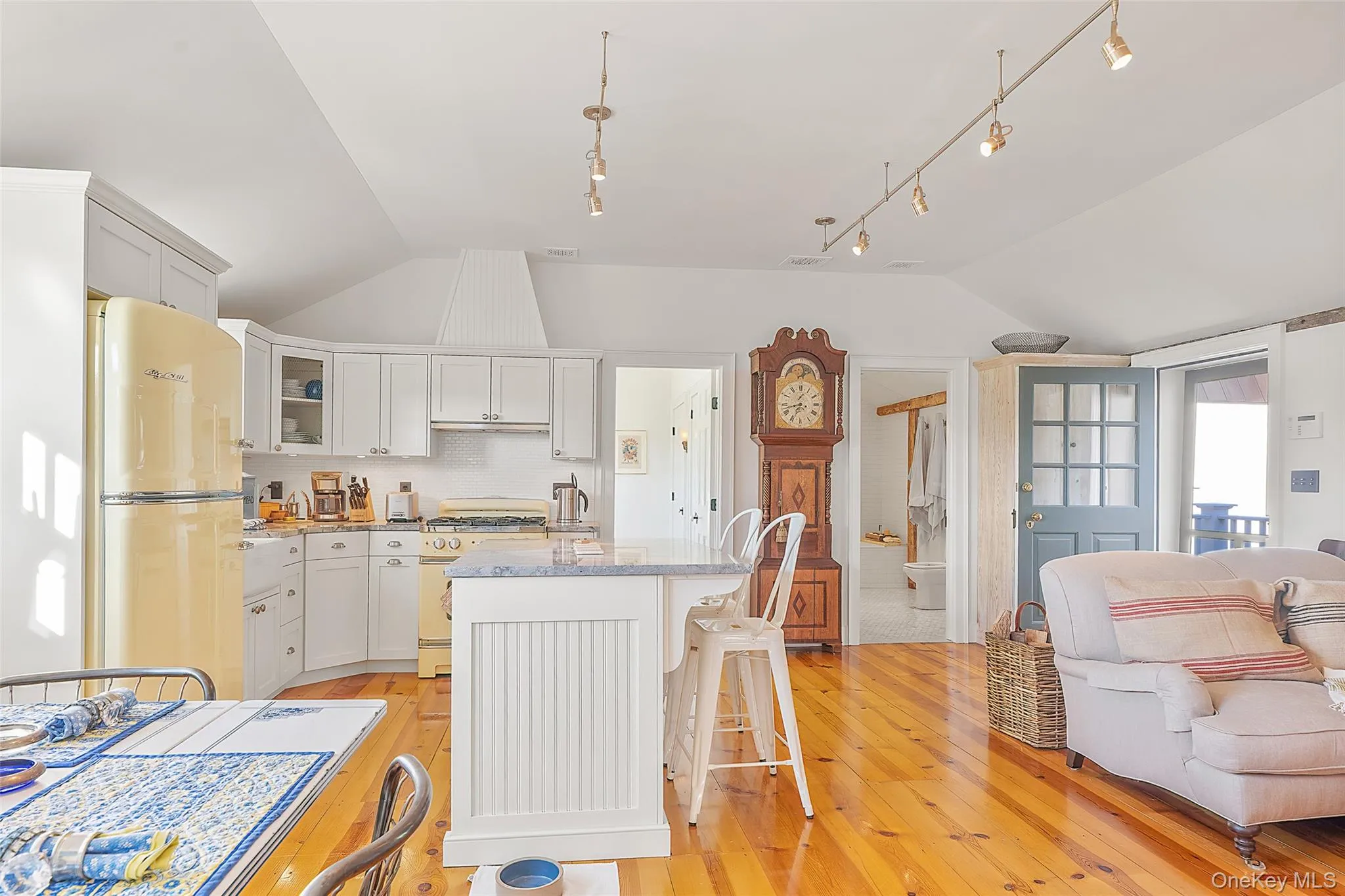 Kitchen featuring lofted ceiling, glass insert cabinets, freestanding refrigerator, white cabinets, and light wood-style floors Kitchen featuring lofted ceiling, glass insert cabinets, freestanding refrigerator, white cabinets, and light wood-style floors