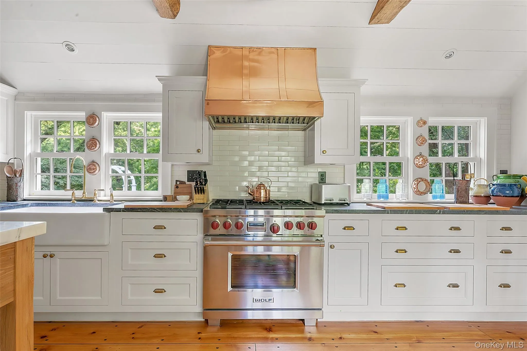 Kitchen with white cabinets, custom range hood, designer stove, and backsplash Kitchen with white cabinets, custom range hood, designer stove, and backsplash