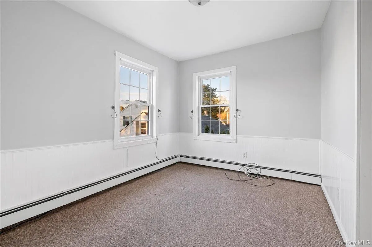 Carpeted spare room featuring wainscoting and baseboard heating Carpeted spare room featuring wainscoting and baseboard heating