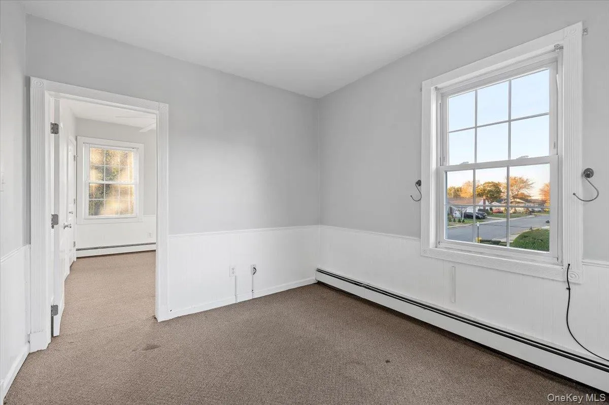 Carpeted empty room with baseboard heating and wainscoting Carpeted empty room with baseboard heating and wainscoting