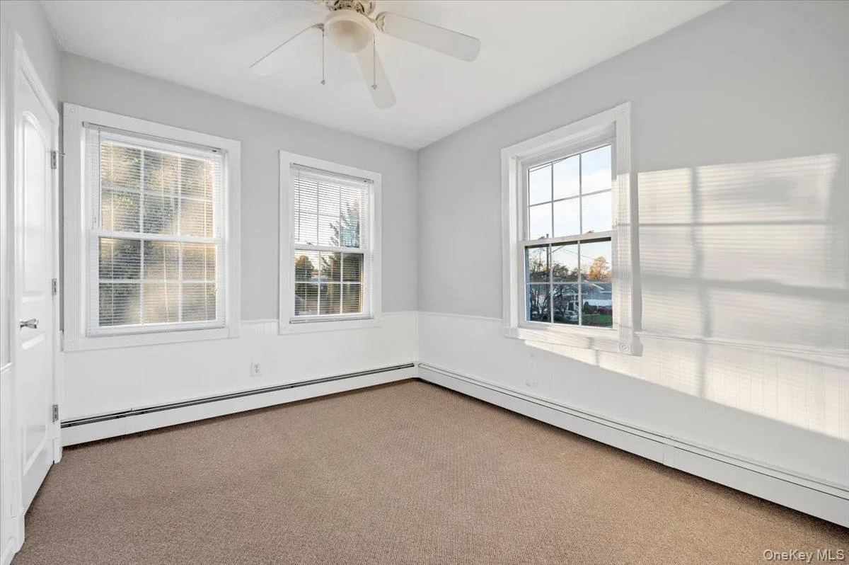 Empty room featuring baseboard heating, carpet, and a ceiling fan Empty room featuring baseboard heating, carpet, and a ceiling fan